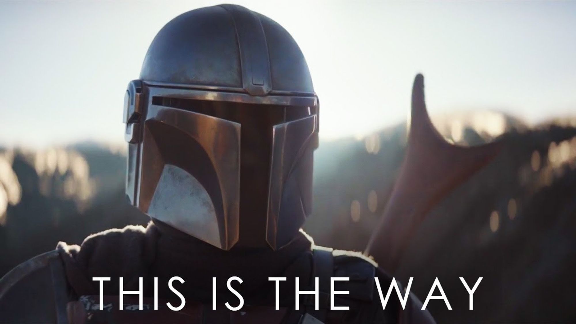 Din Djarin, the main character from the show "The Mandalorian", in foreground, with its helmet on. "This is the way" is written at the bottom of the image.