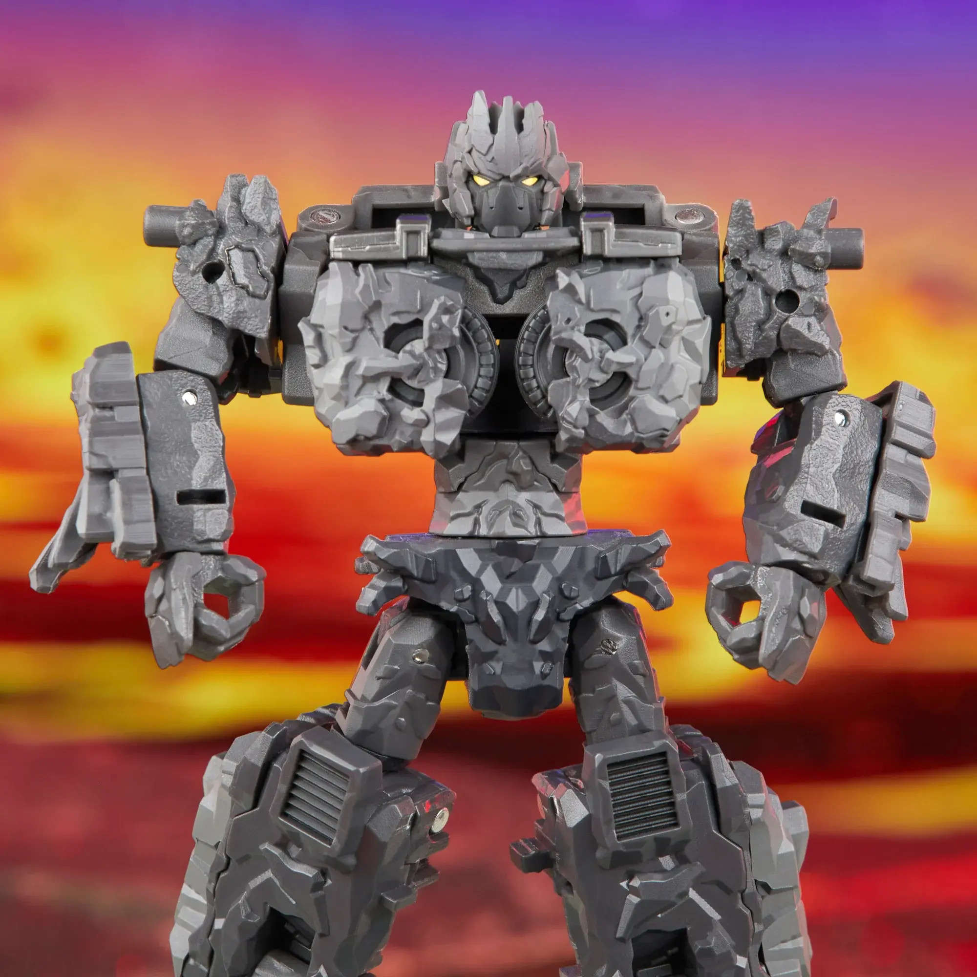 An Image of Transformers Legacy Magneous who looks like they're made out of sharp-ish grey volcanic rocks, their central chest section is comprised of two wheels in close proximity with a small gap between them