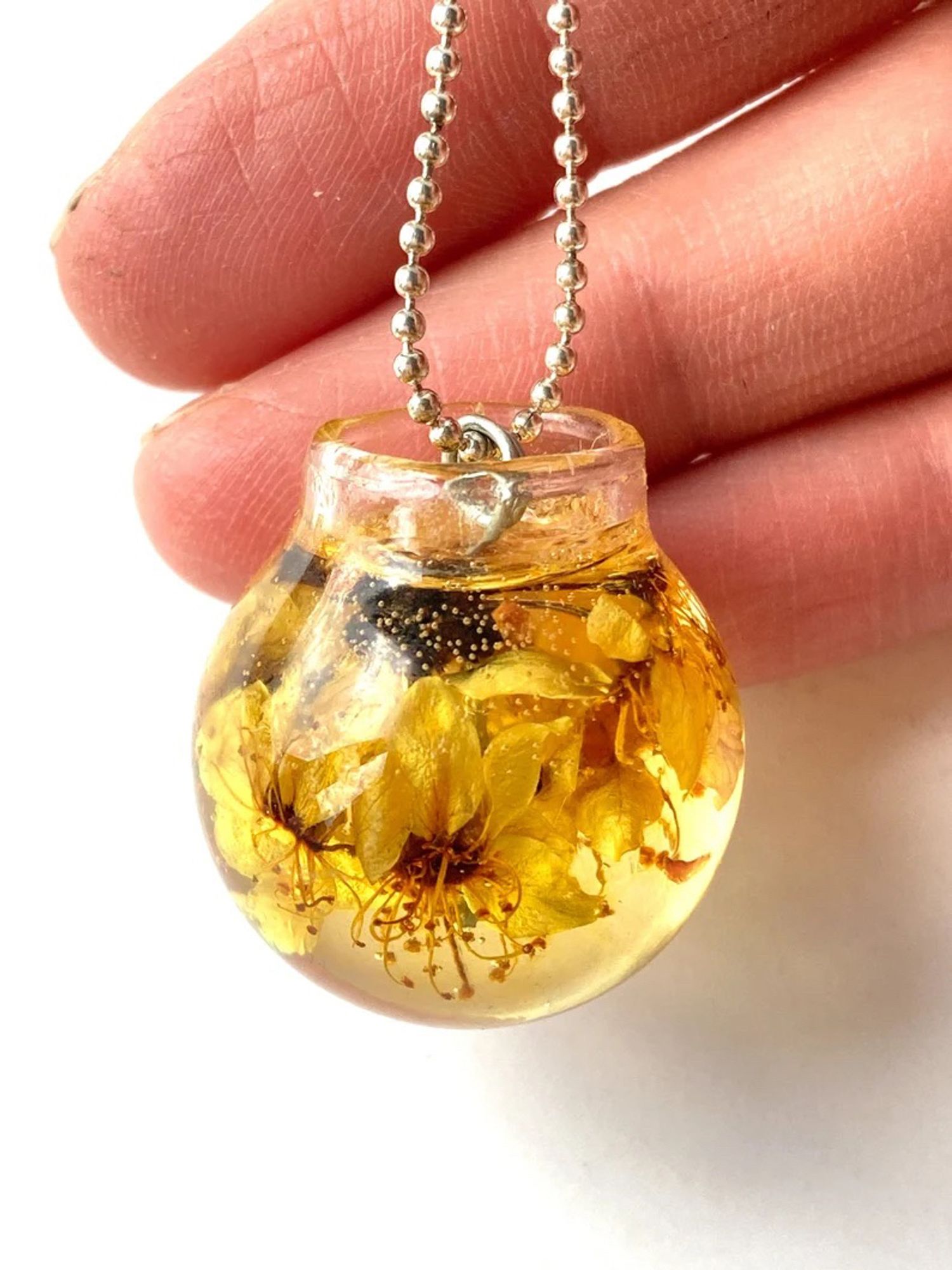 Necklace with glass ball pendant and flowers in resin