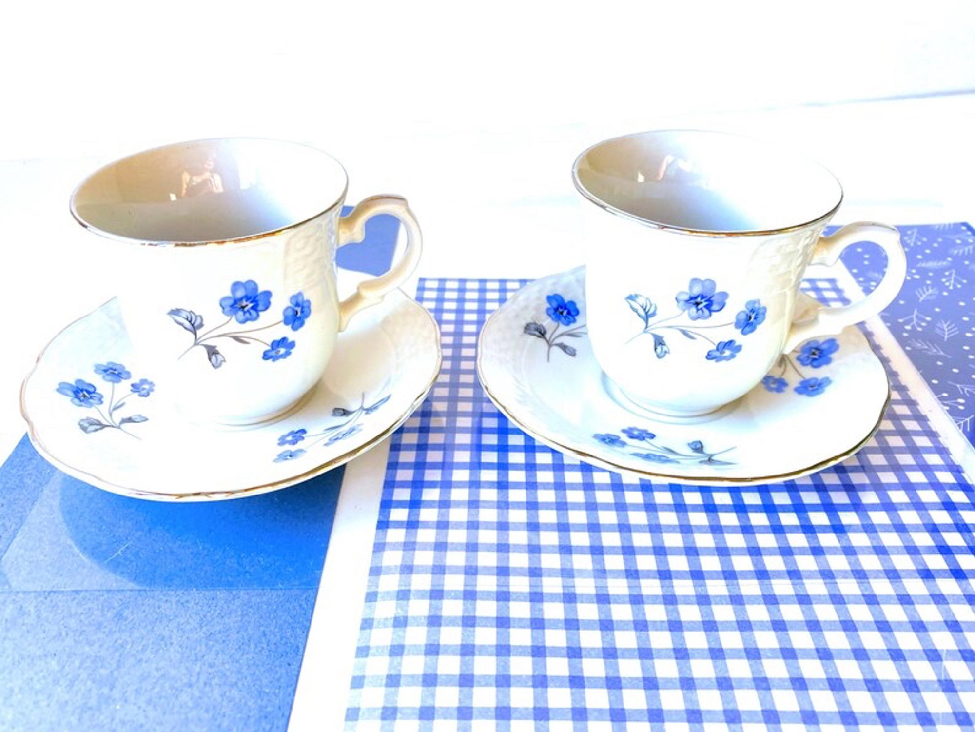 set of two white old fashioned porcelain teacups and saucers with lovely blue flowers