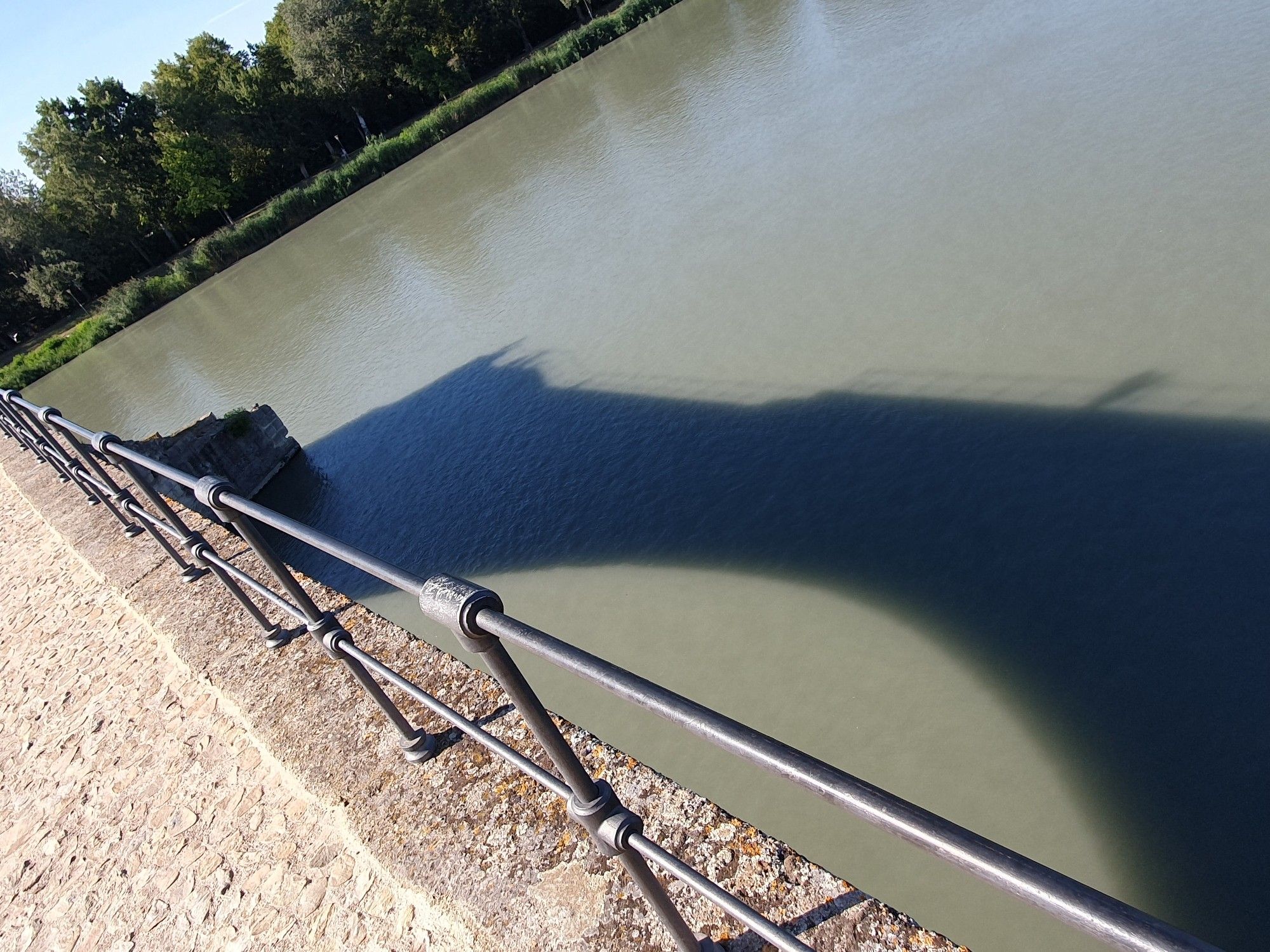 Photo again taken from the bridge in Avignon this time in the other direction to the far bank of the river Rhône. The shadow of the bridge is seen in the water revealing that only part of the bridge remains, as it stops abruptly half way across the river.