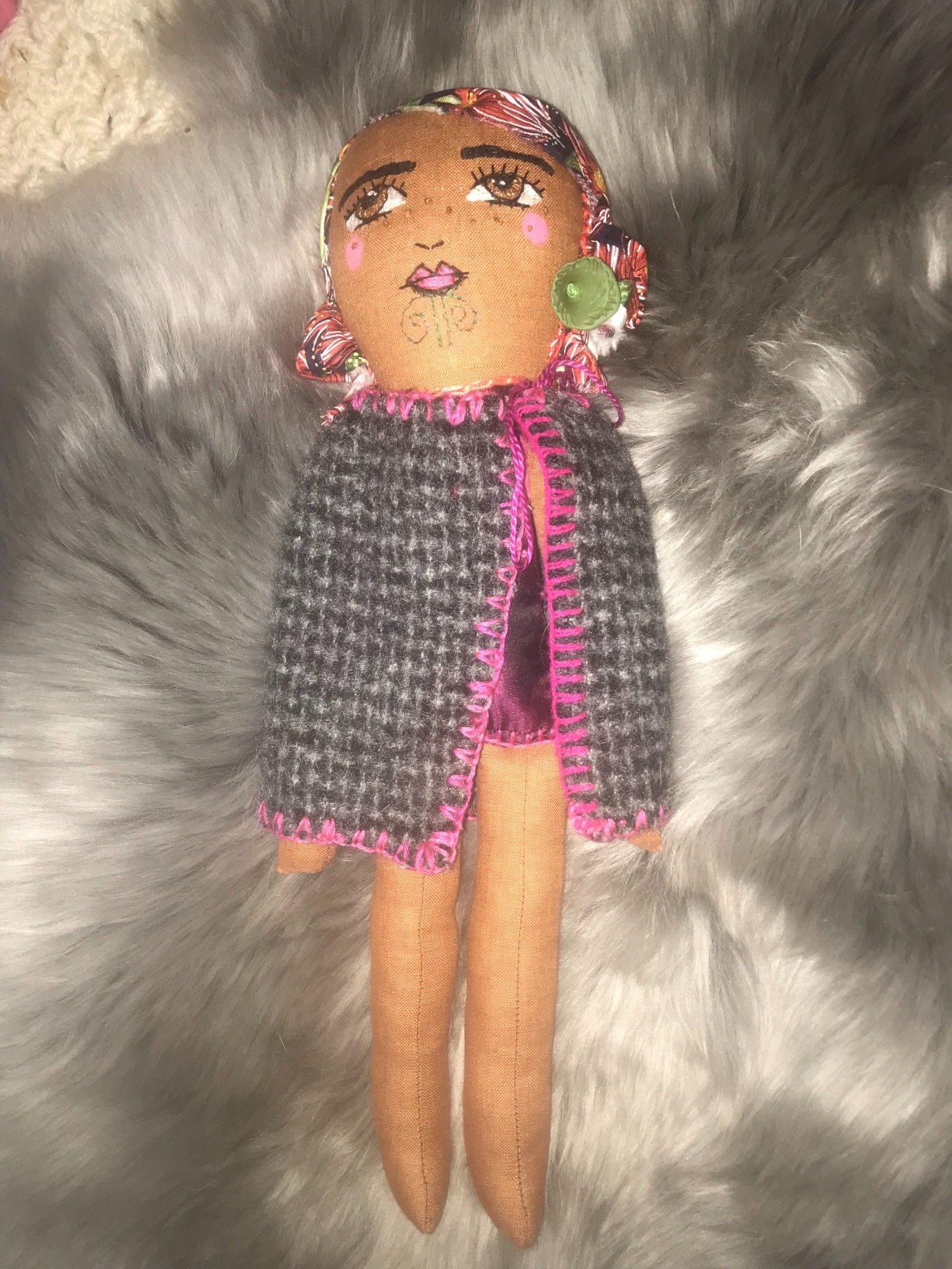 Baby doll has beautiful Pohutukawa hair, her big brown eyes are embordered, as are her lovely features, she has moko kauae which is delicately sewen in green thread. She is wearing a finely crafted coat