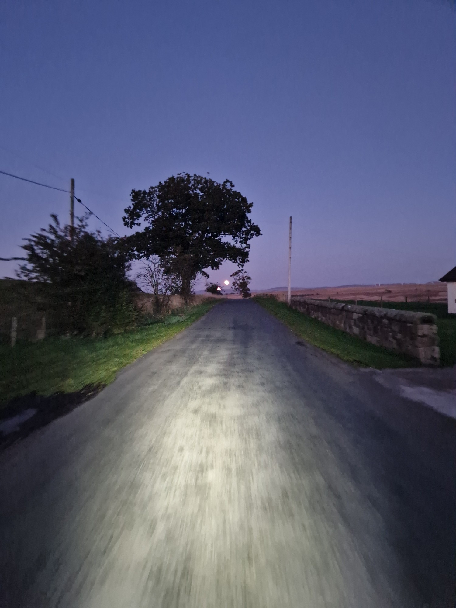 Quiet road after dark in West Lothian, cycling towards the hunter moon on the horizon.