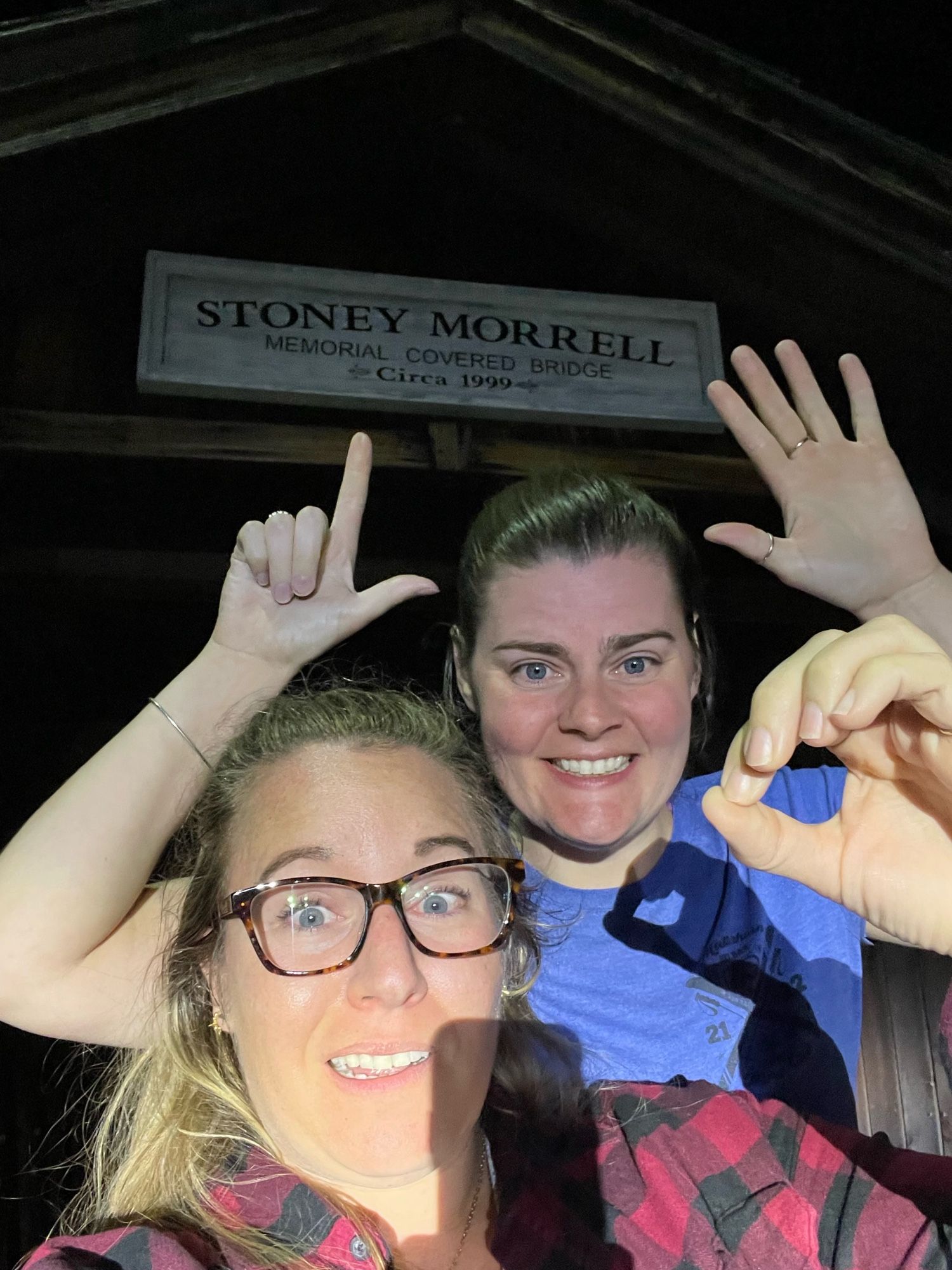 Gf and I holding up 7 fingers and a 0 in front of this tiny adorable covered bridge that looks like it was made for children