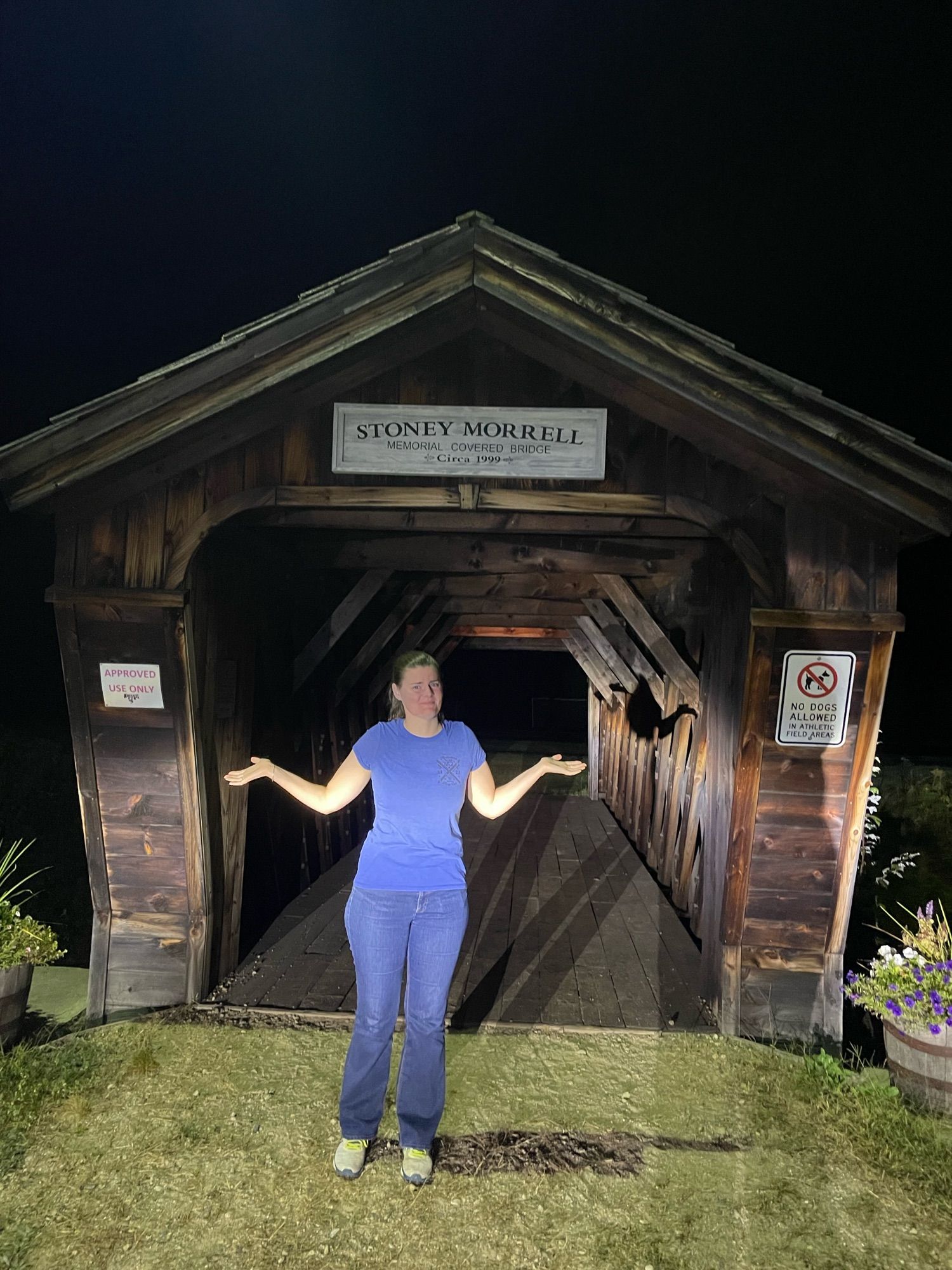 Gf shrugging in front of wee covered bridge