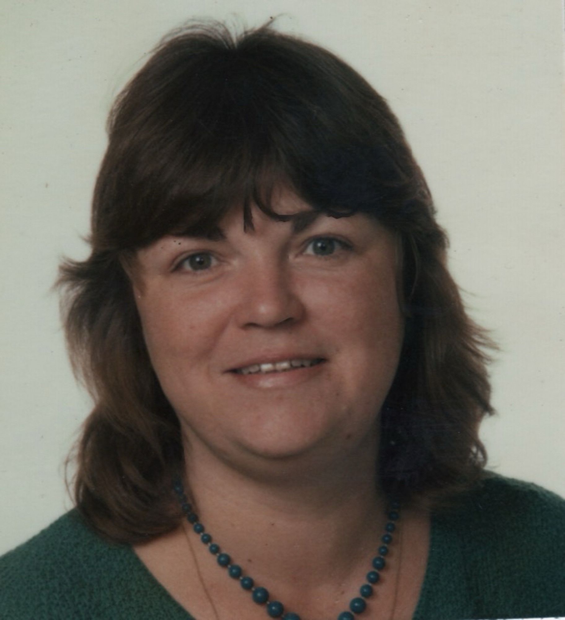 Woman with feathered hair and a green blouse.