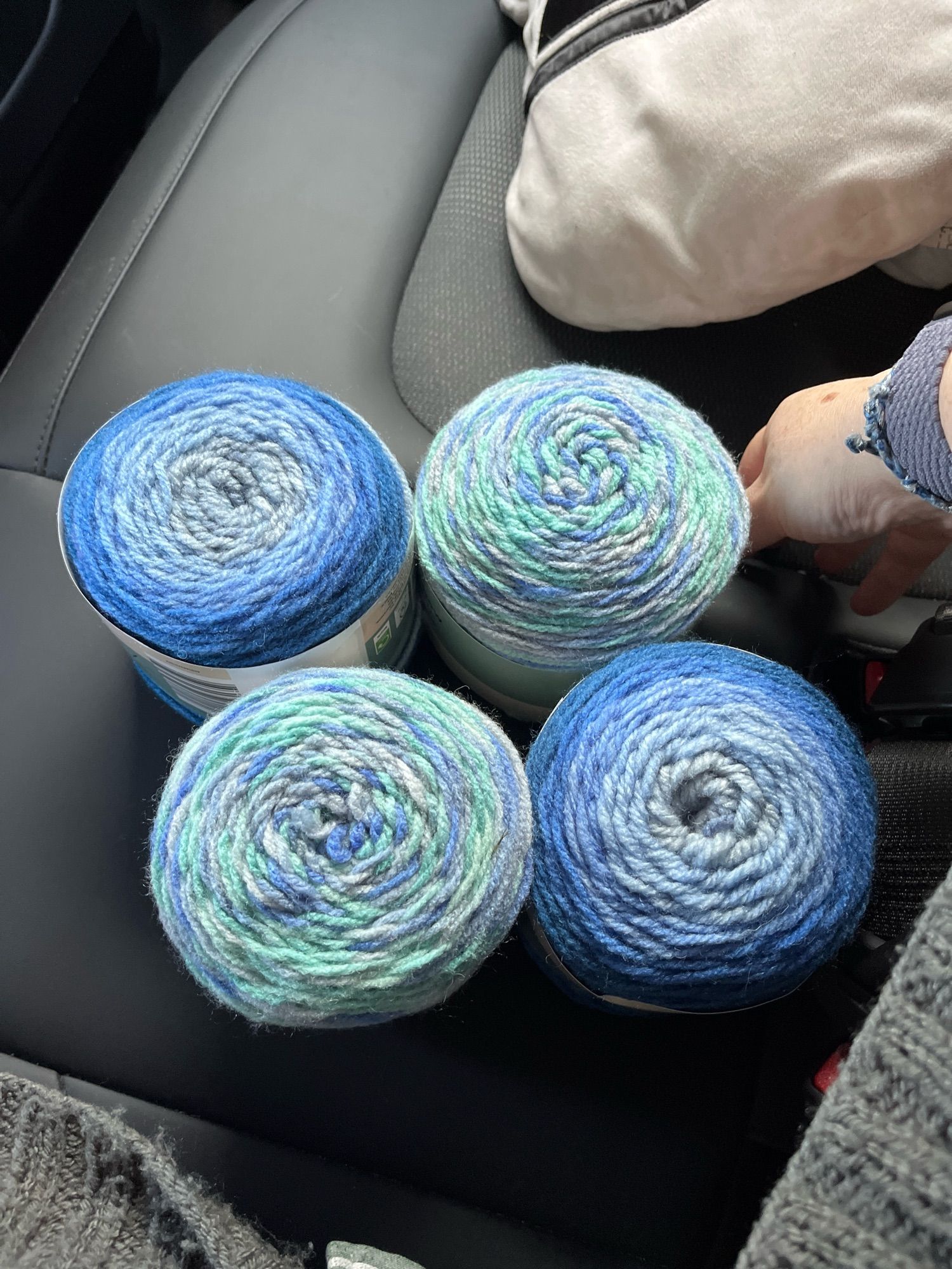 Four balls of yarn in shades of blue, pale green and pale purple