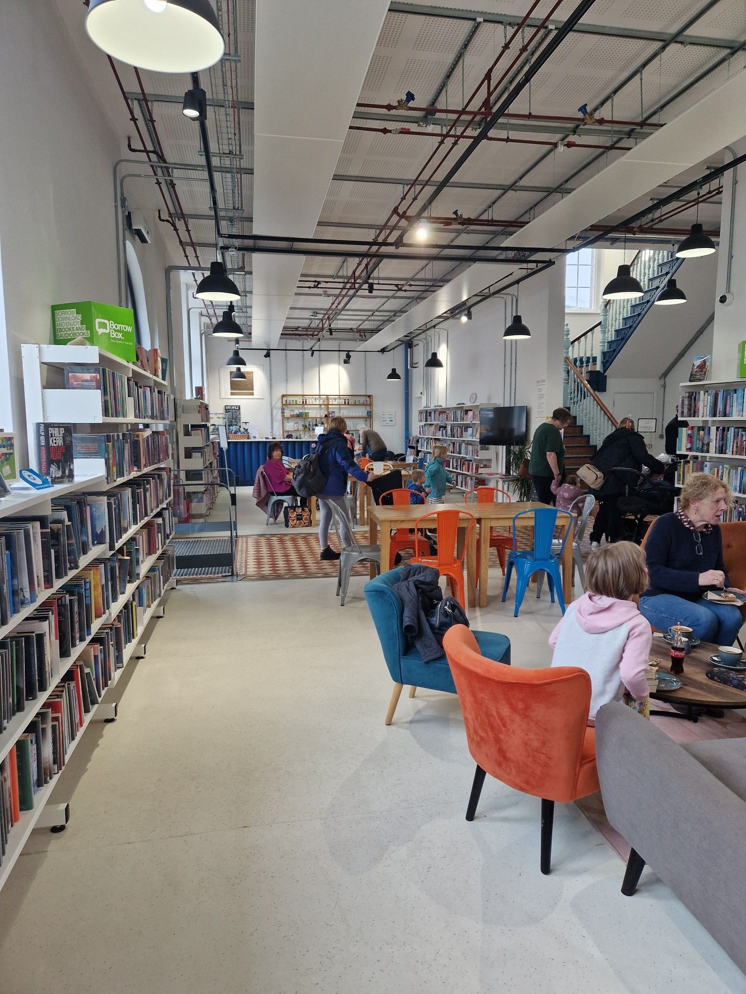 The interior of Liskeard Library, where people are gathered together, socialising and reading. Credit - Real Ideas Organisation.