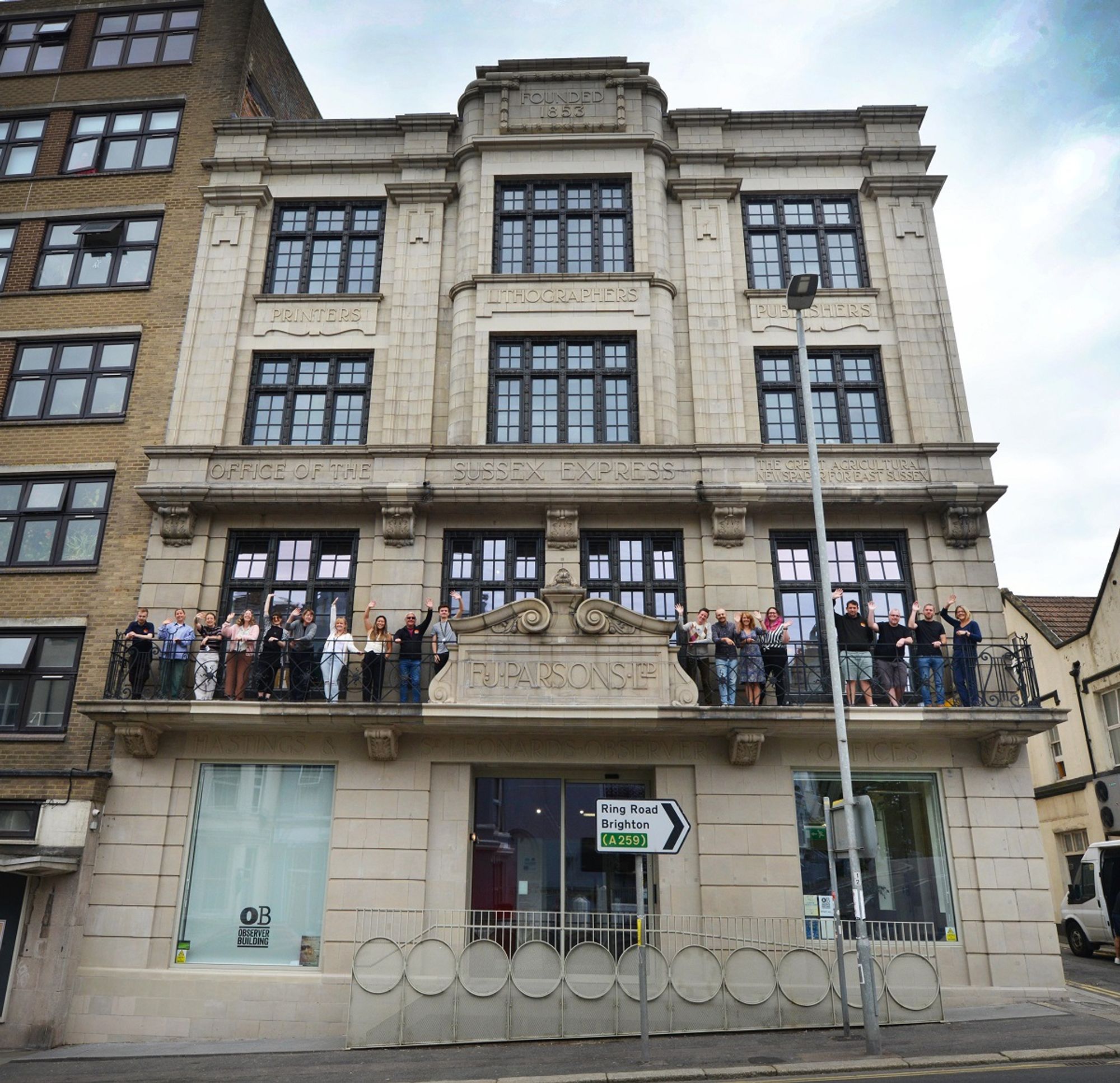 The Hastings Commons team is standing on the balcony of the Observer Building in Hastings. Credit - Justin Lycett.