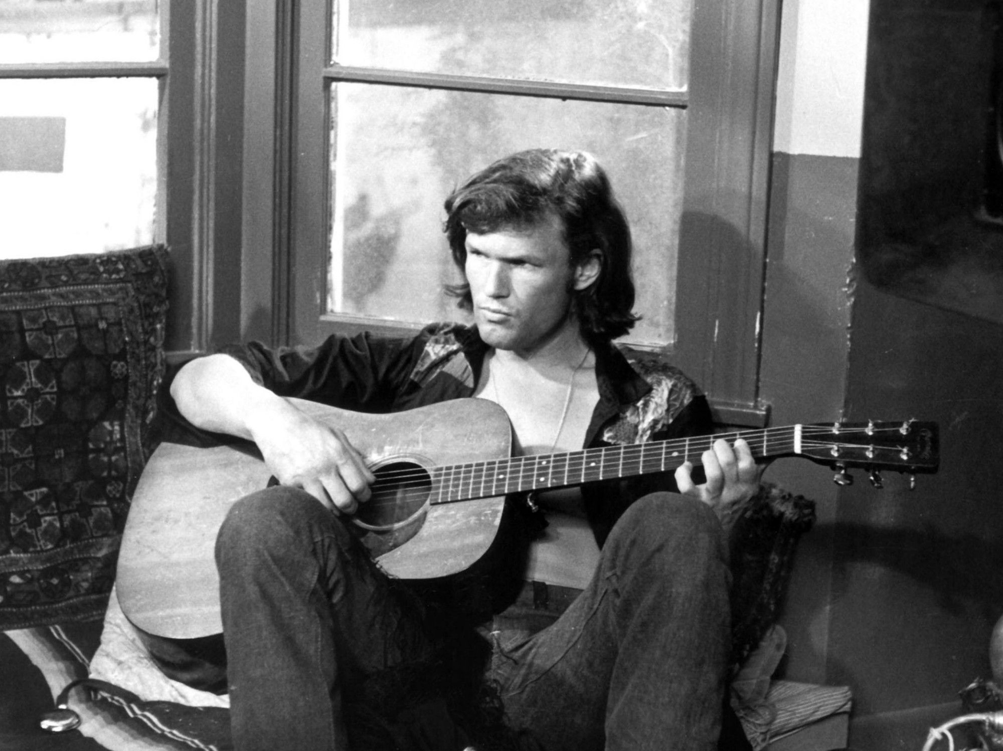 young hot kris kristofferson smoldering over an acoustic guitar