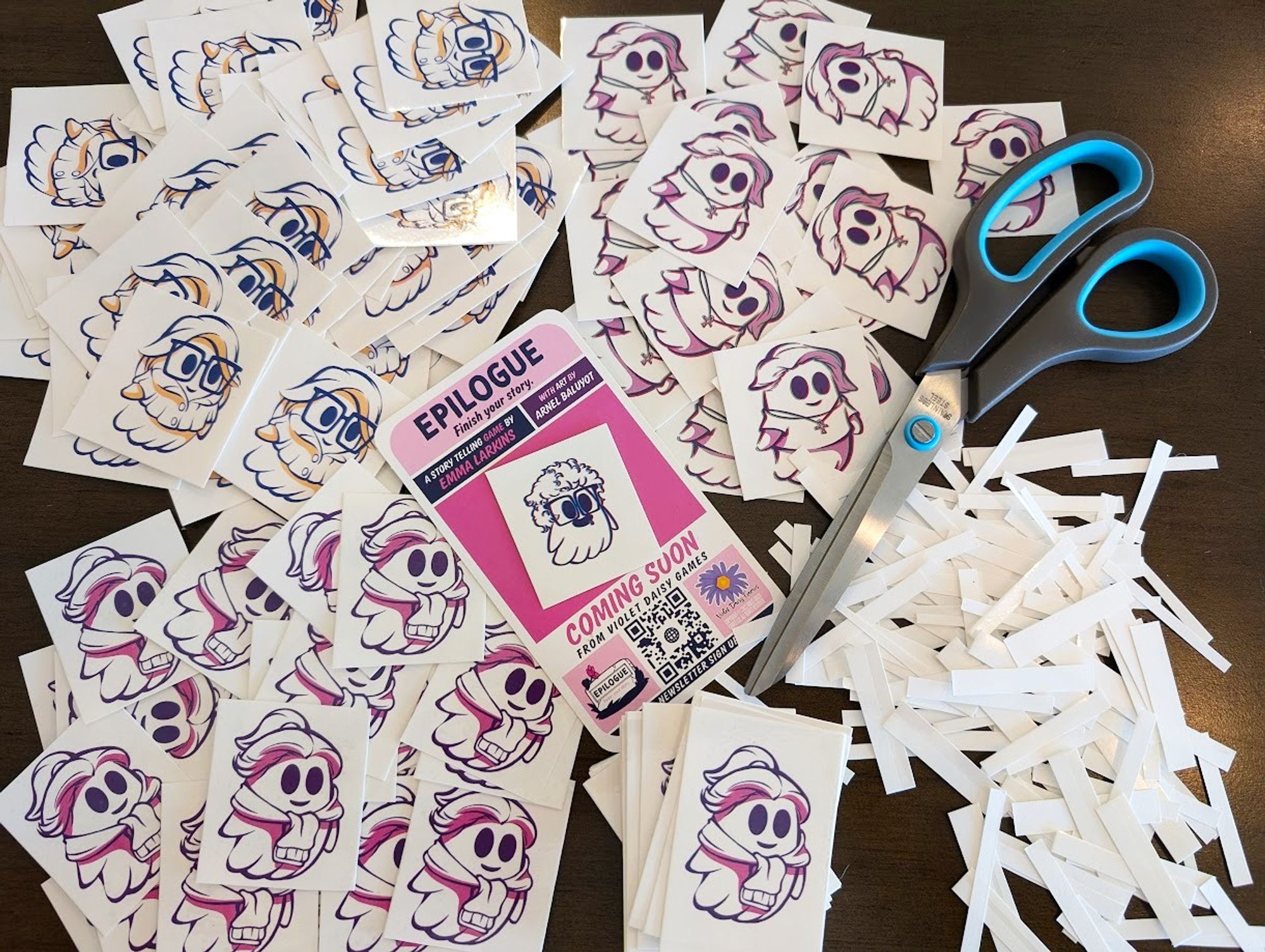 A bunch of Epilogue ghost tattoos being trimmed down to fit on the Epilogue promo cards with a pair of scissors.