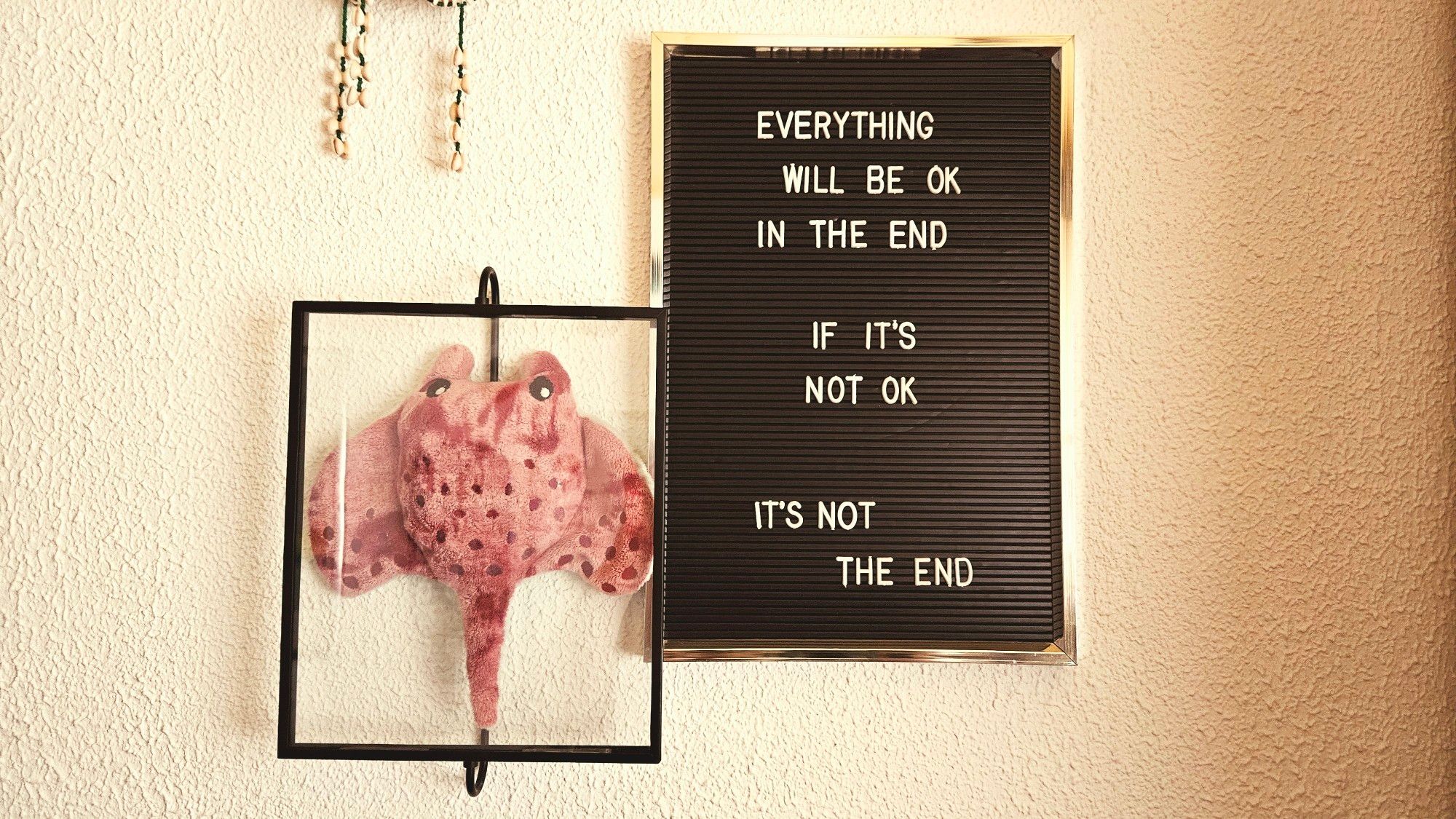 Witte muur met twee lijstjes. In de één zit een knuffel rog, de ander is zwart met witte tekst:
Everything will be ok in the end
If it's not ok, it's not the end