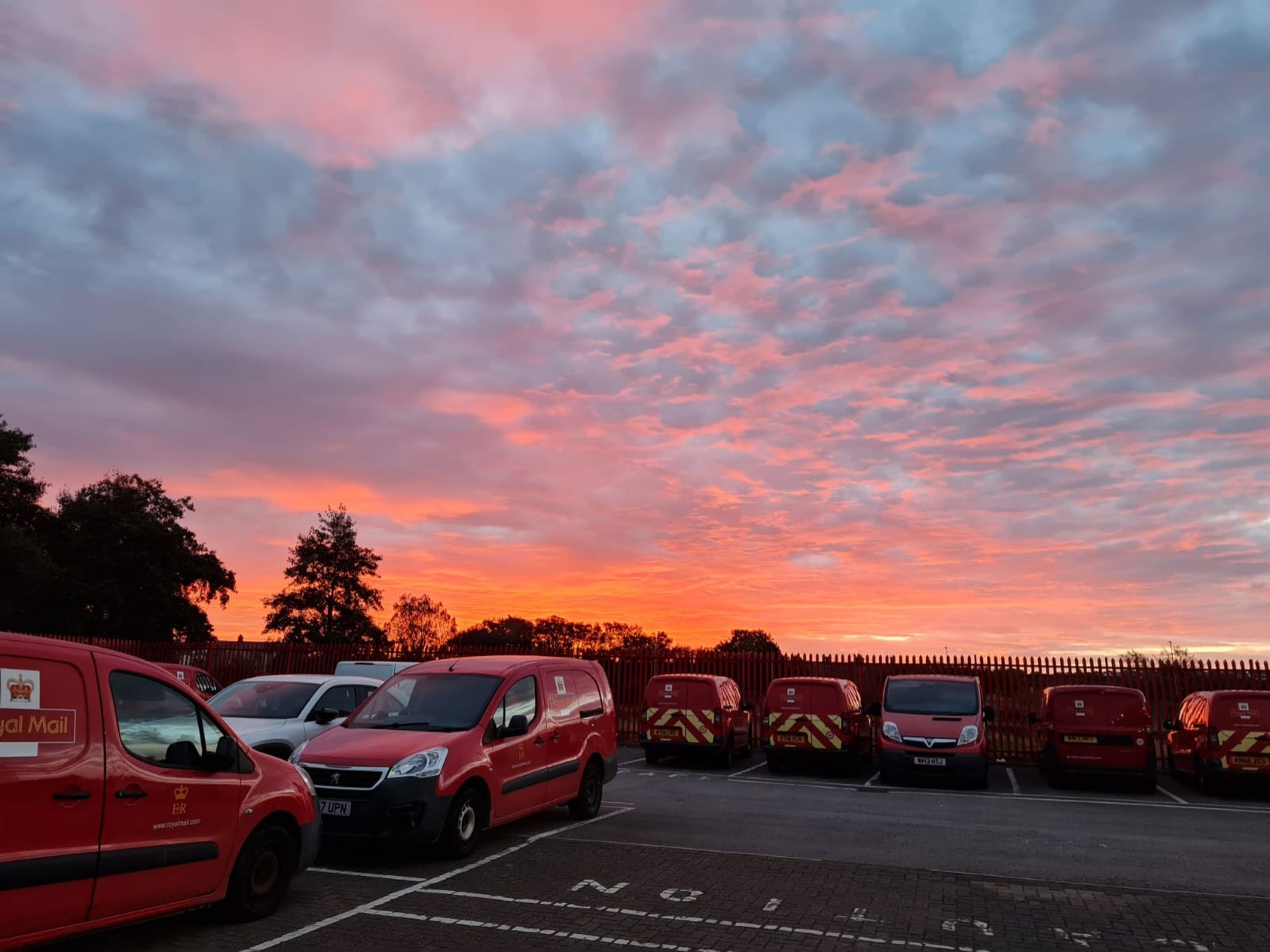 Red sky in the morning over the red posties vans at Royal Mail Delivery Office Workington.