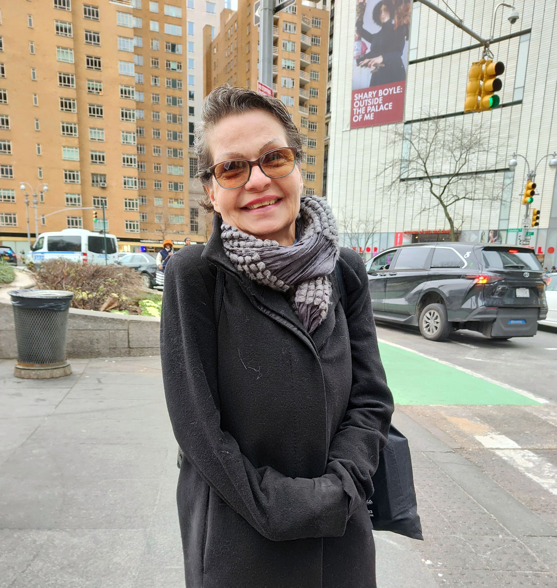 An older activist from Germany is wrapped up for winter time she smiles for a photo and behind her is New York City in Columbus Circle. she was there at the protest in solidarity and we had a meaningful conversation about Genocide