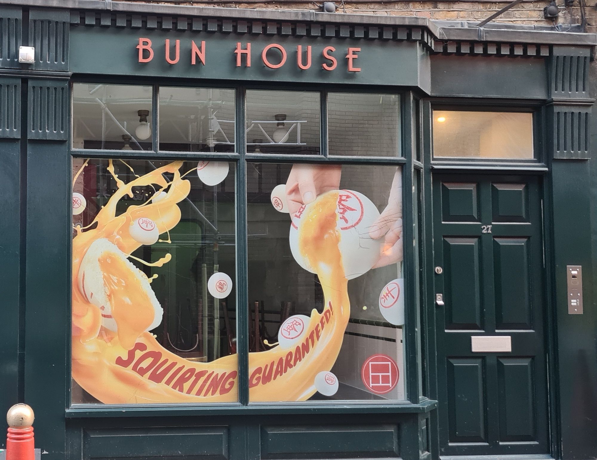 A Bun House in Soho, with a bun being opened and liquid pouring out, with the slogan "Squirting Guaranteed".