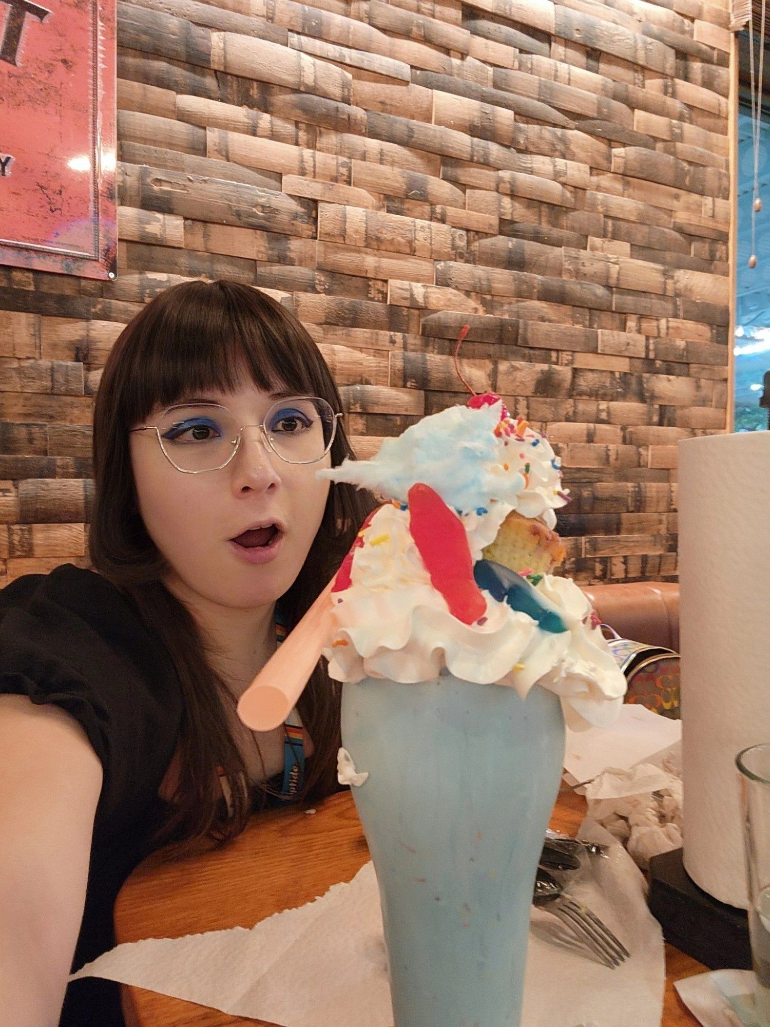 photo of myself with my mouth agap. staring in surprise at the sheer size and presentation of the birthday cake shake we ordered. it was super big, almost as tall as the paper towel roll next to us. and almost same width too. they even managed to fit a cupcake in there!!