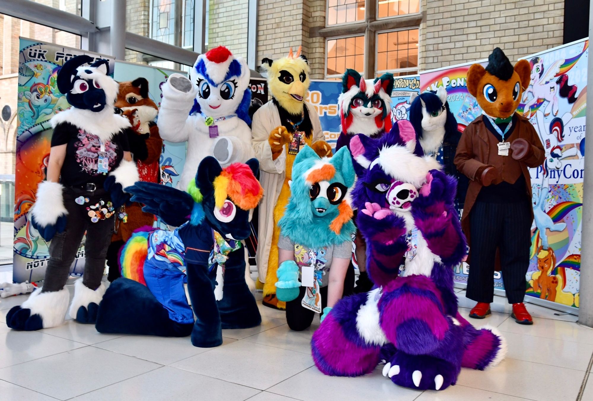 A group of fursuiters gathering for a photoshoot with con banners in the background.