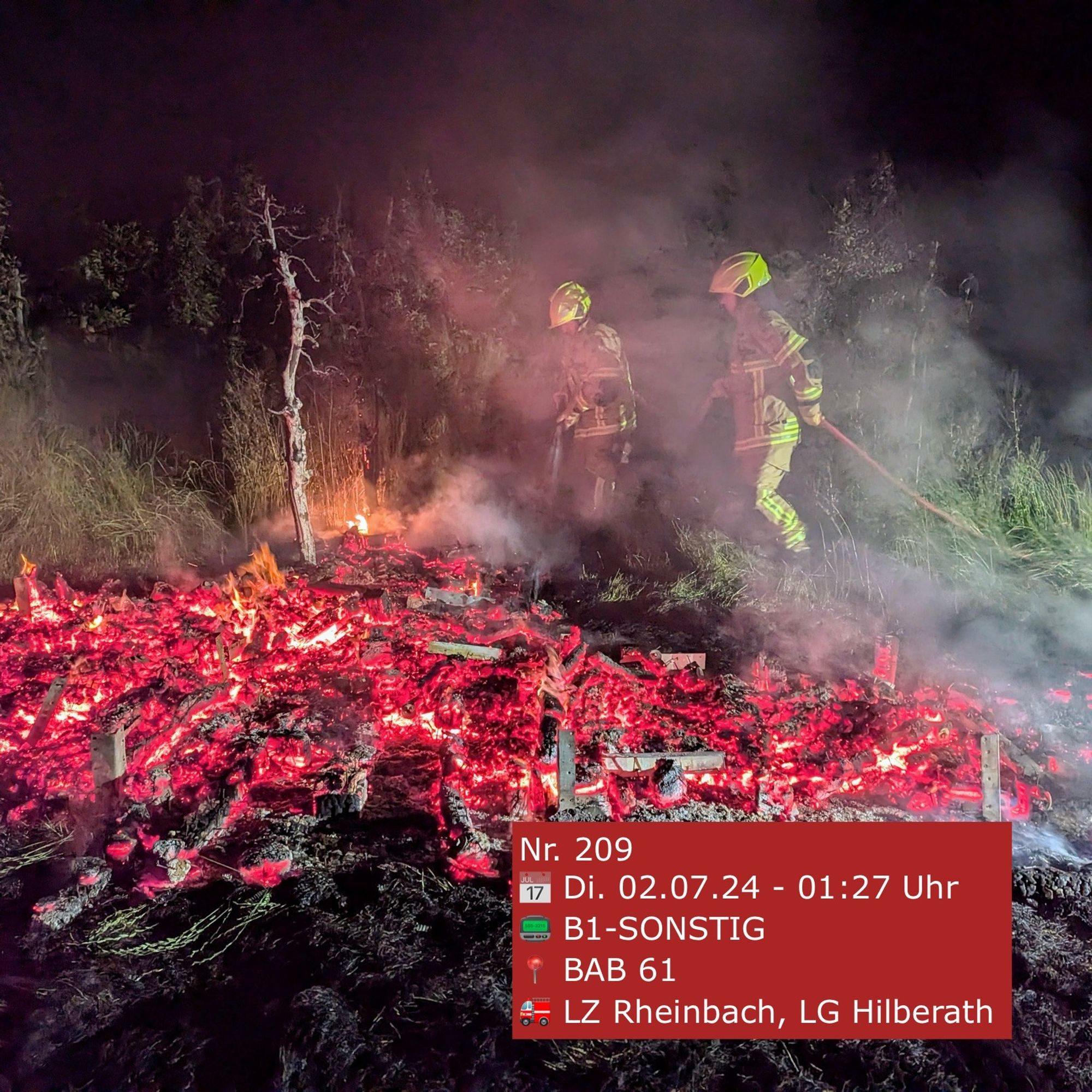 Feuerwehrleute löschen einen Kleinbrand. Im Vordergrund Glut.