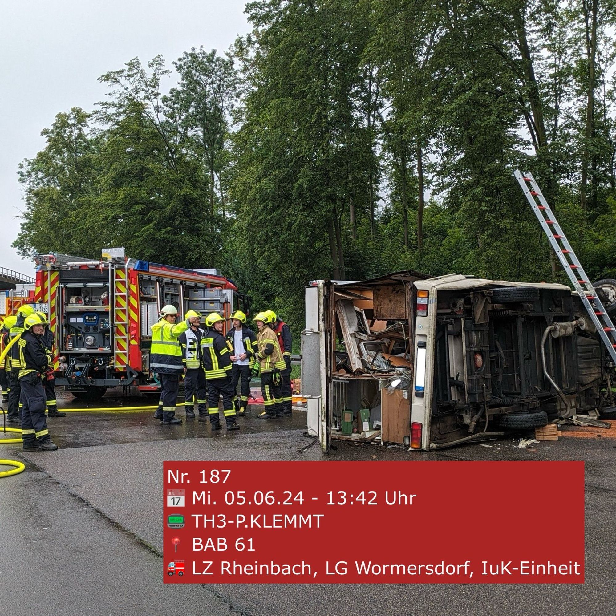 Ein verunfalltes Wohnmobil liegt auf der Seite; im Hintergrund ein Feuerwehrfahrzeug und Einsatzkräfte.