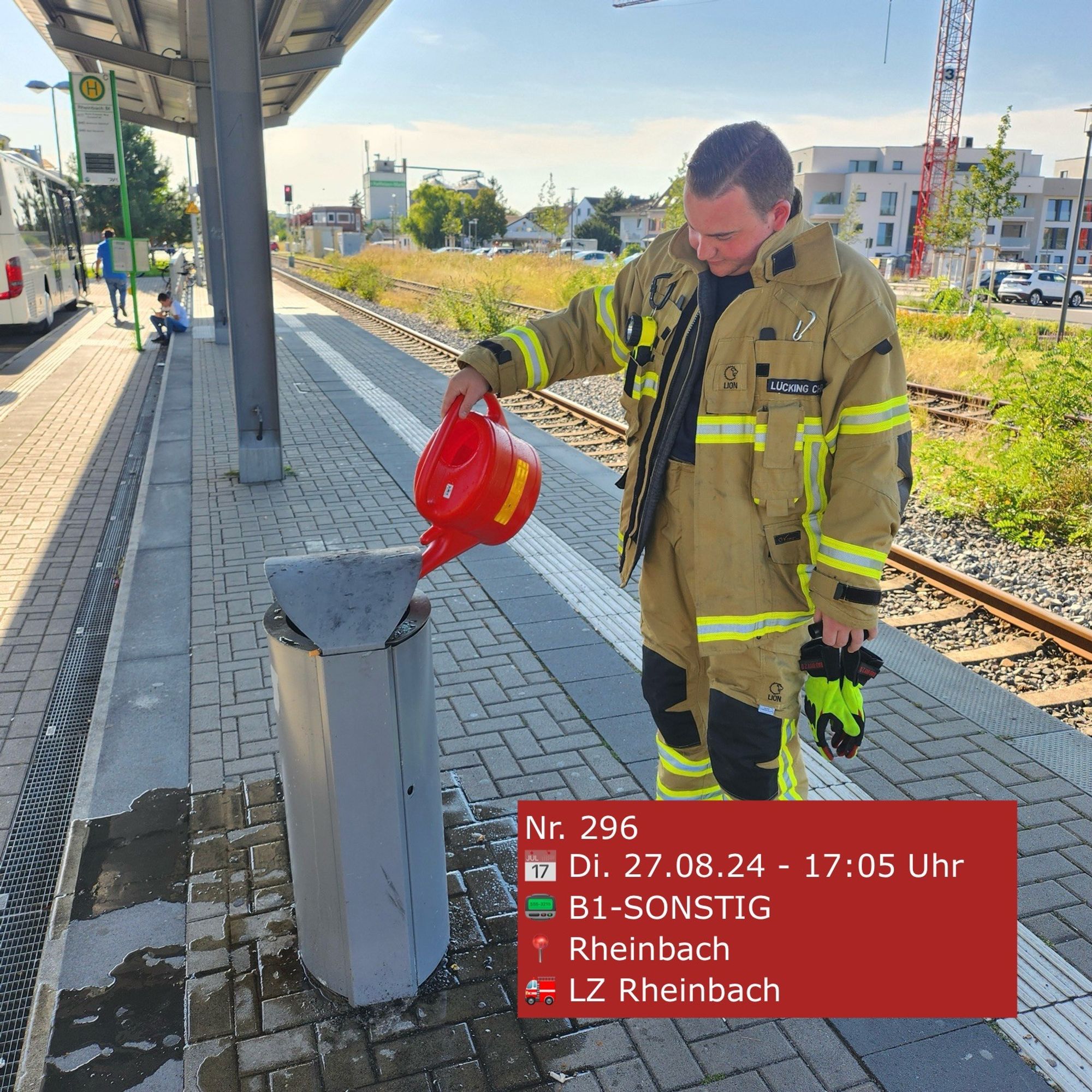 Ein Feuerwehrmann löscht mit einer Gießkanne einen Mülleimerbrand.