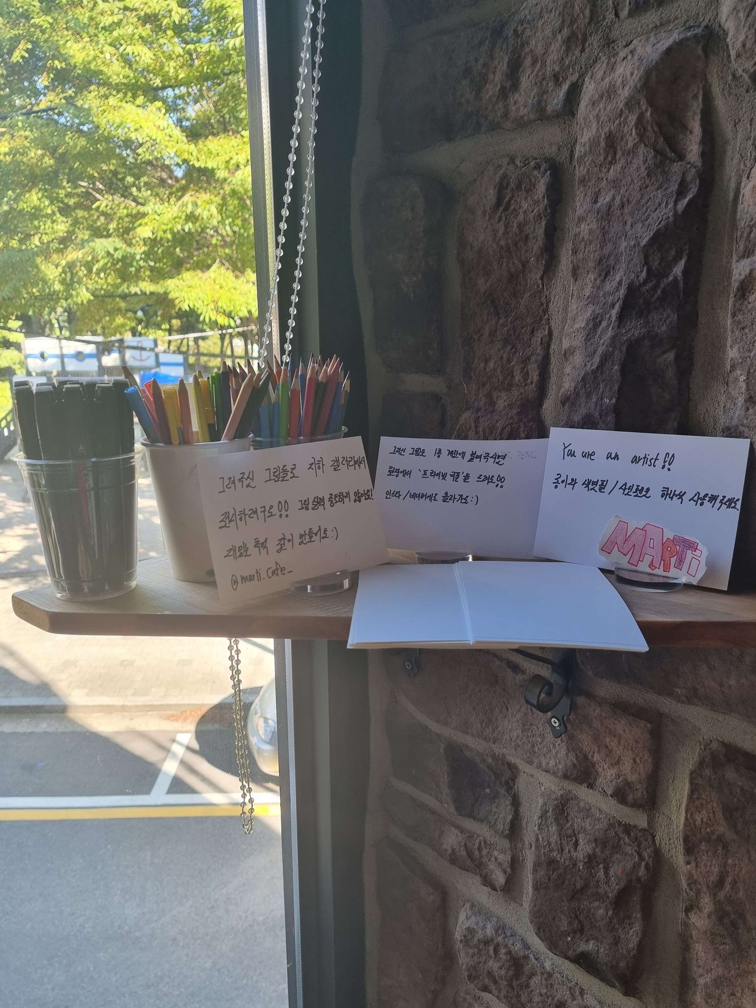 Two plastic cups holding pencils and colored pencil in front of paper and notes with writing on them.