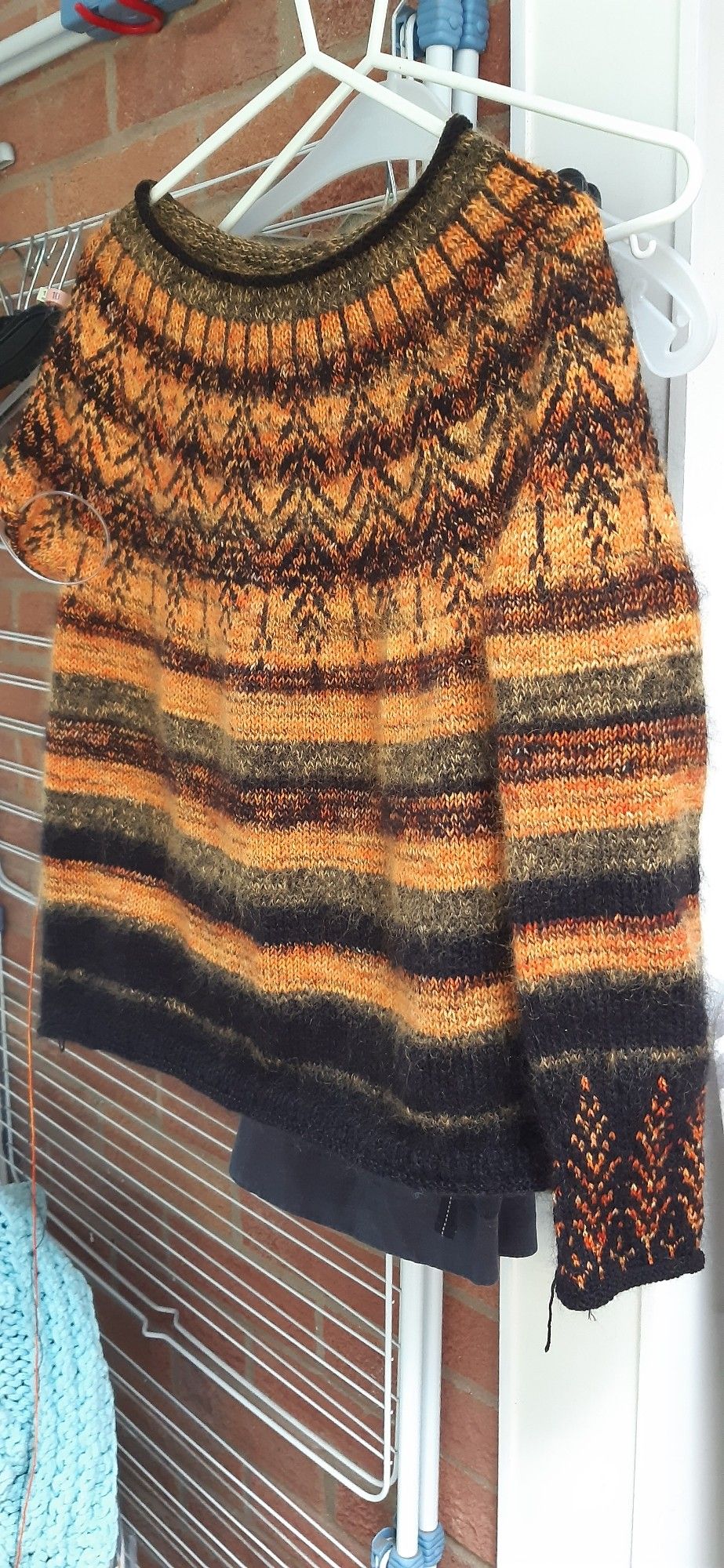 Orange and black striped jumper with feather motif on yoke and sleeve