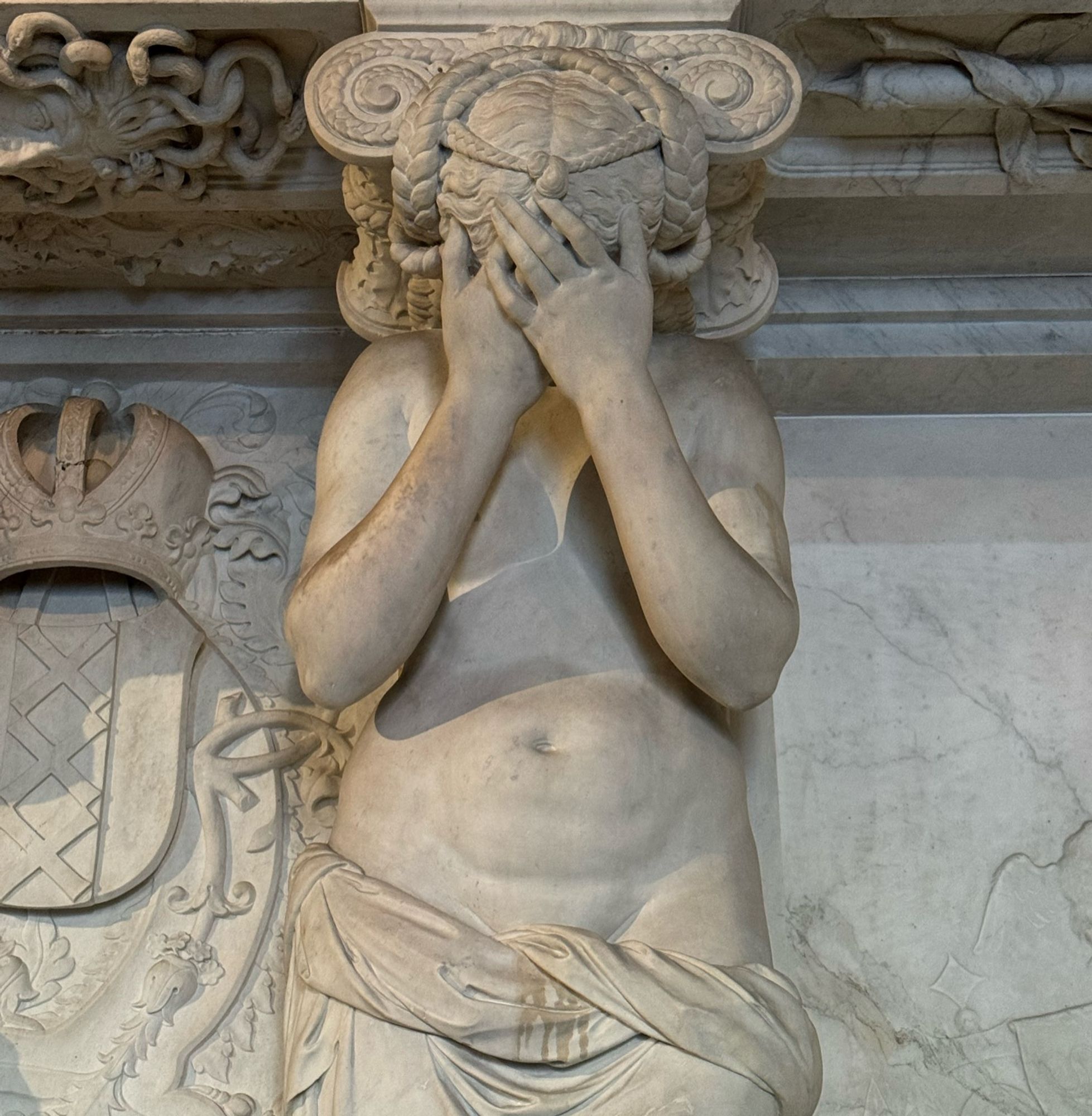 Statue at the Dutch Royal Palace in Amsterdam, where a woman has her hands over her face