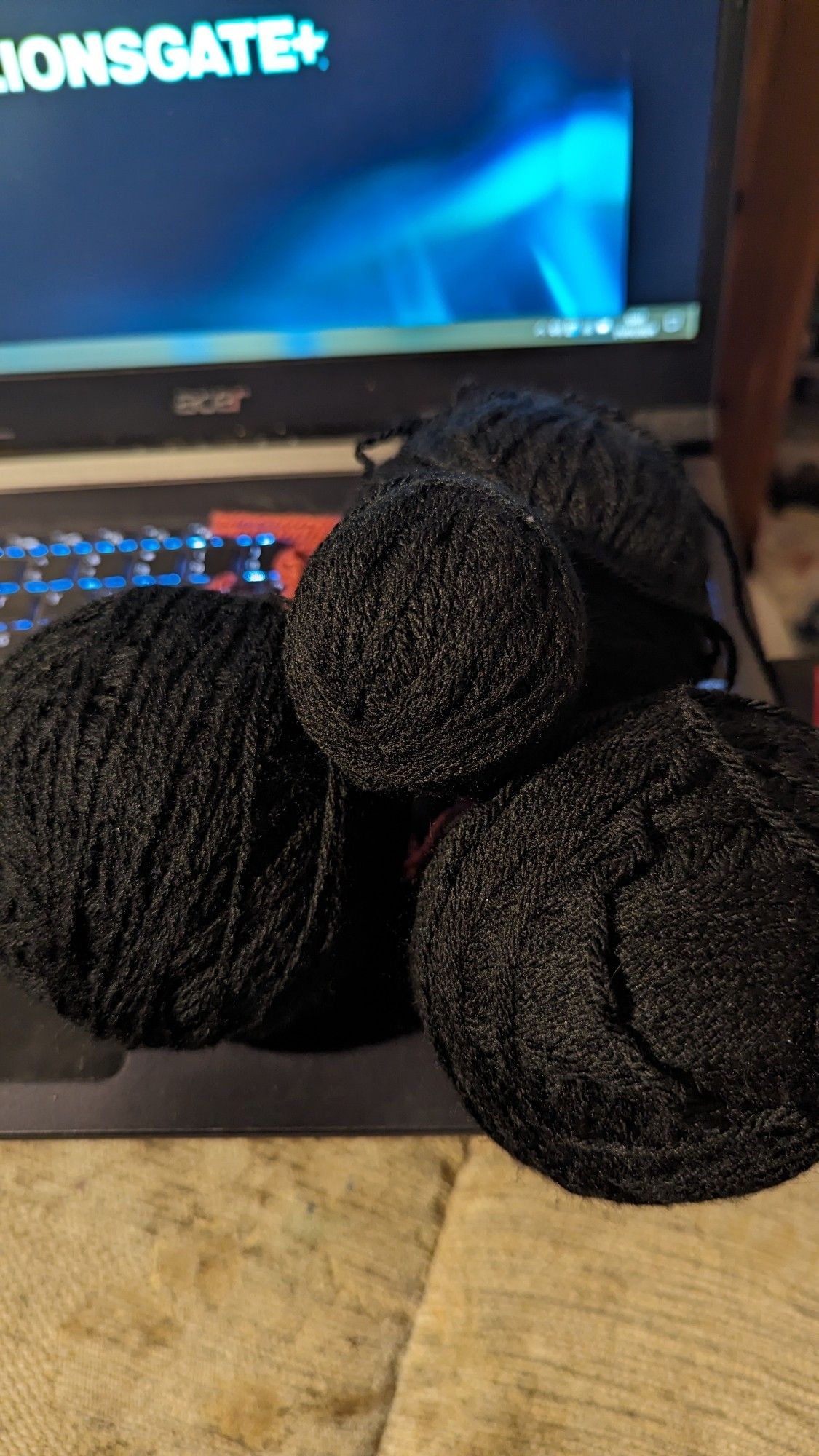 Four balls of black yarn, in a pile on a laptop.