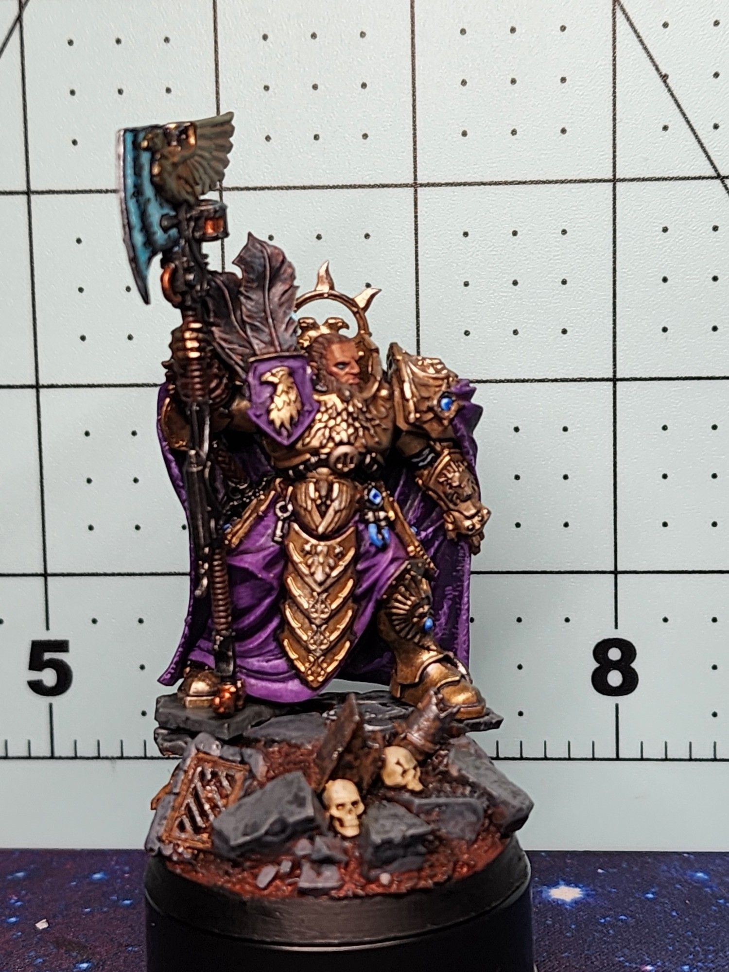 A Warhammer 40k Custodes, with gold armor and a purple cloak with blue axe.