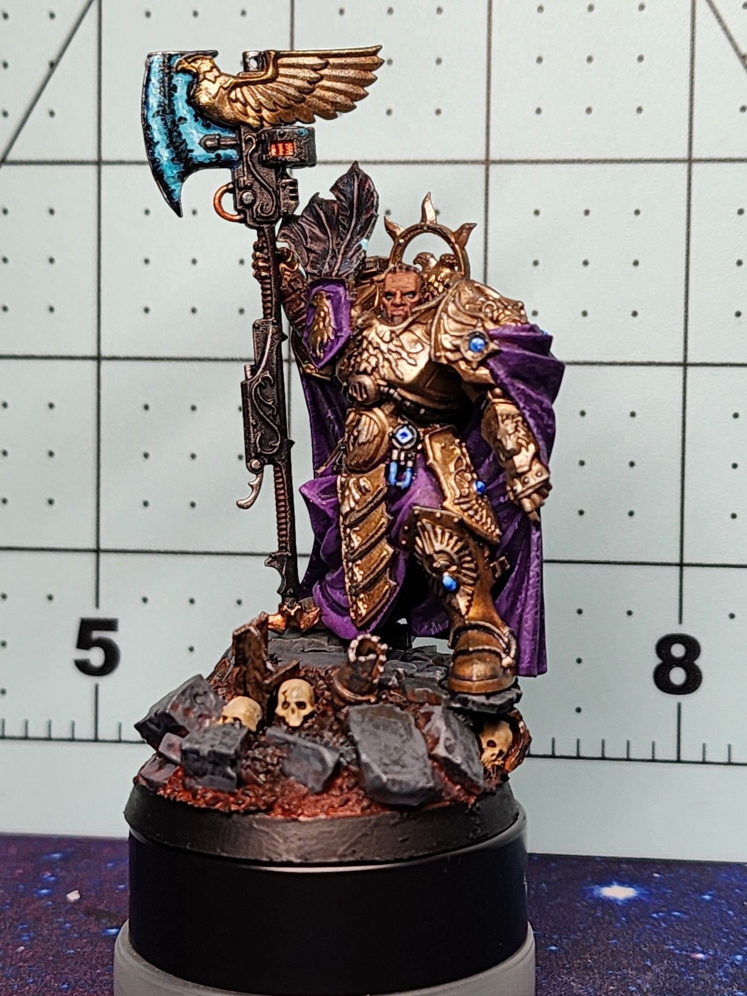 A Warhammer 40k Custodes, with gold armor and a purple cloak with blue axe.