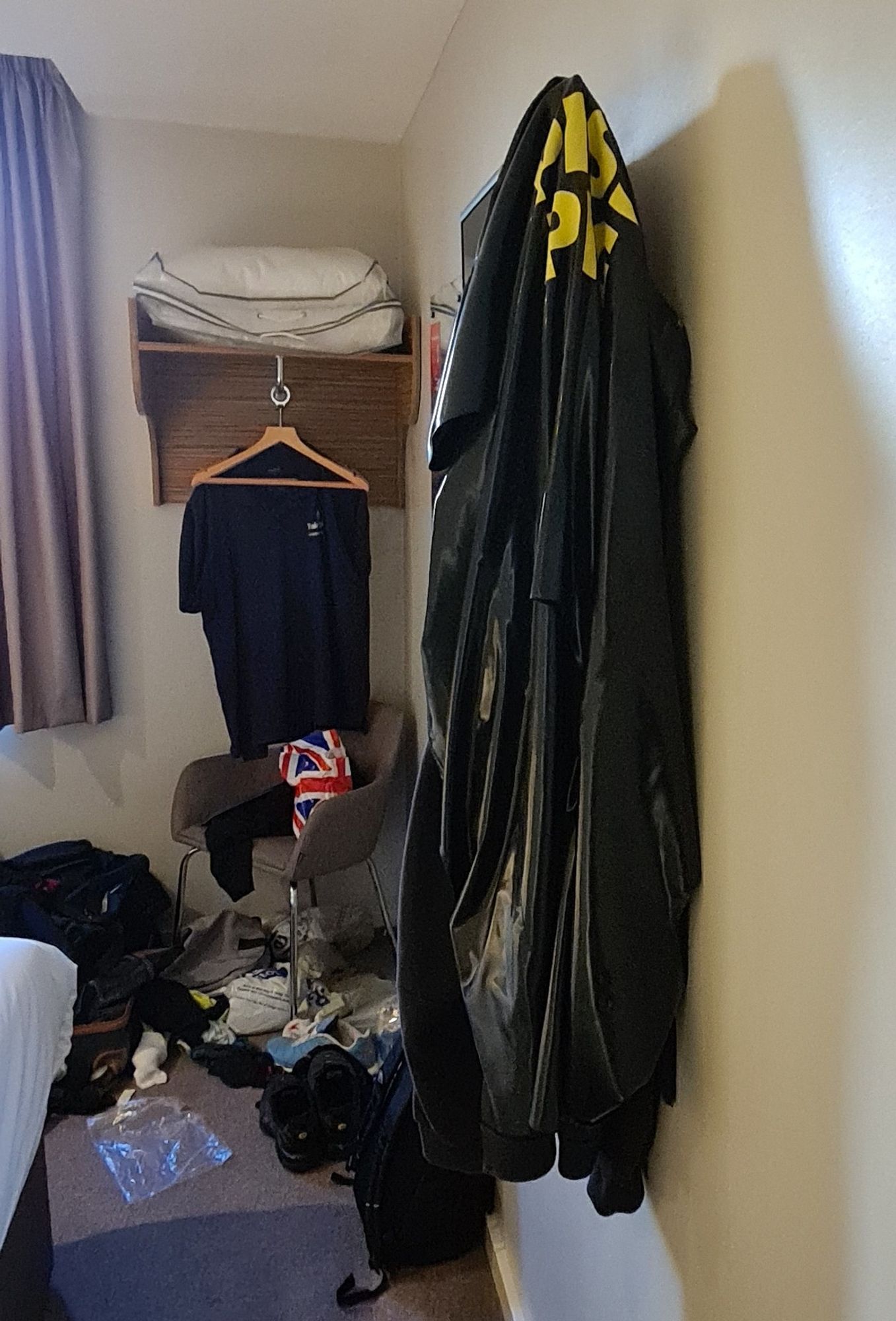 Rubber suit with piss pig on back, hung on corner of tv. Plus mess of clothes and trainers not cleared away.