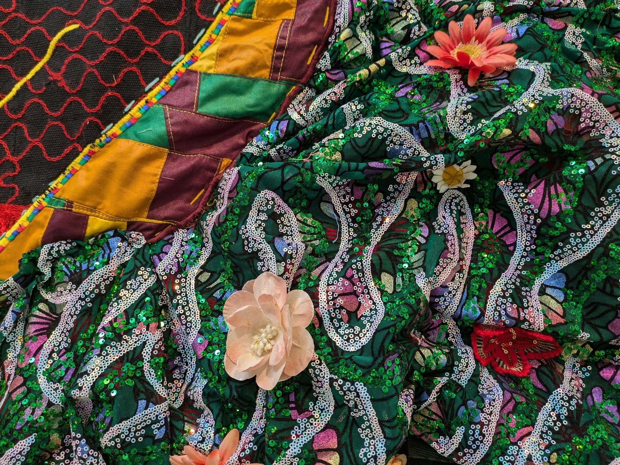 detail of a quilt showing multiple fabrics including bright green and white sequins on a white, green, and pastel highly patterned, bunched fabric with applique flowers in various shades of peach sewn adjacent to other, more matte but also multicolored fabrics. 

Basil Kincaid, Within This Seed Is the Gift of a Thousand Forests, 2024