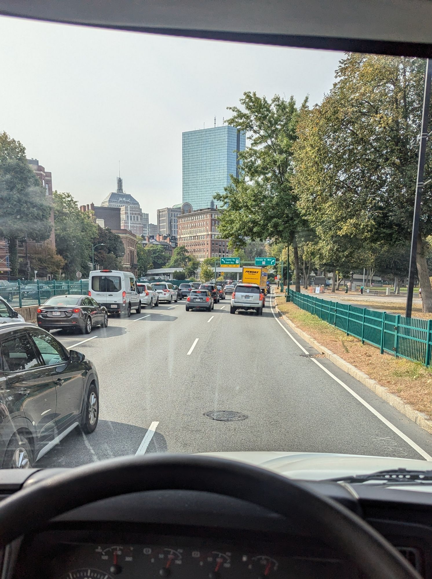 A point-of-view him the driver's seat of a large box truck looking along a packed Storrow Drive. In the distance, another box truck is also stuck in traffic.