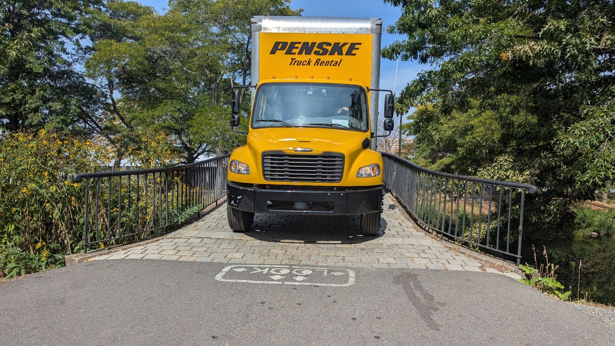 A large box truck shown in the process of driving over one of the foot bridges.