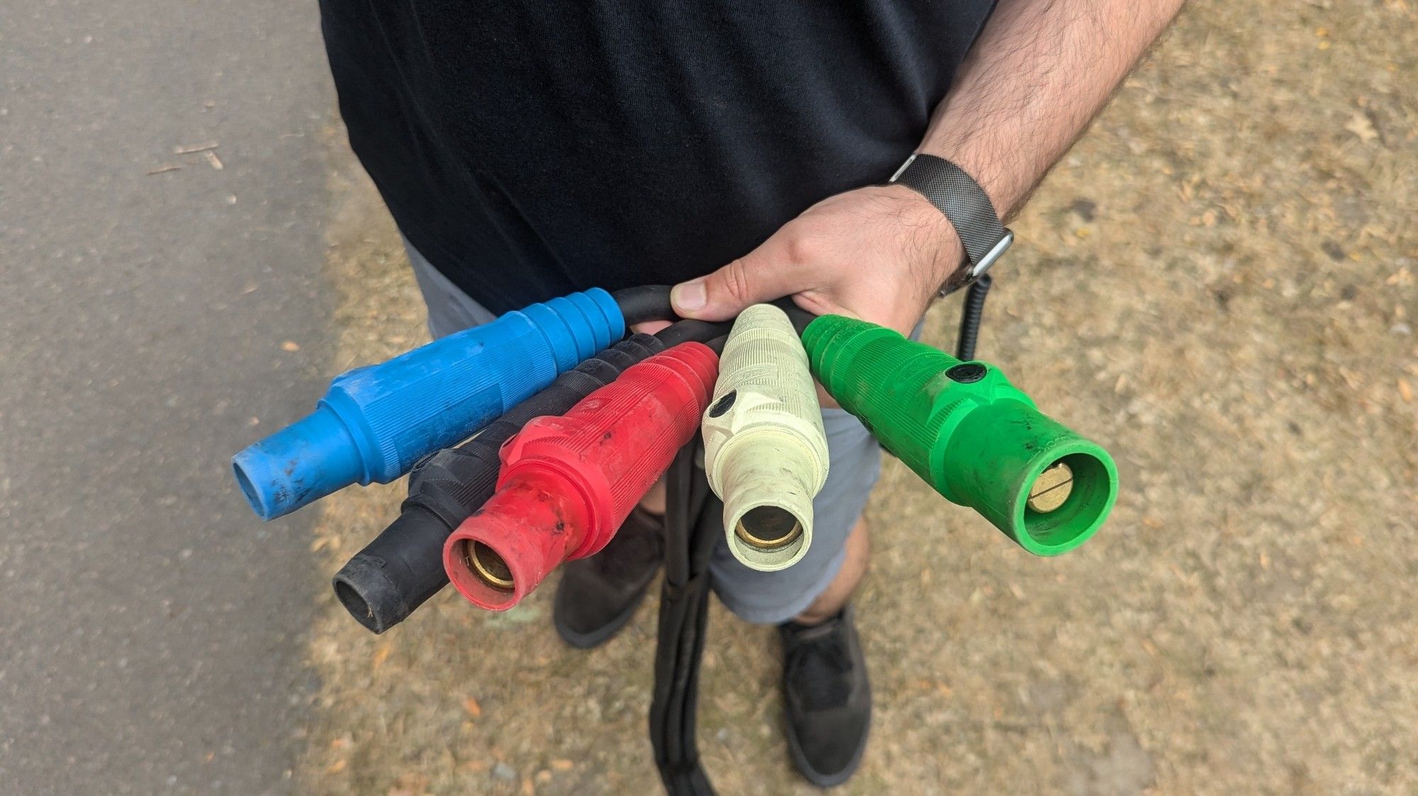 A person holding one end of a feeder set fanned out to display the connectors. The ground cam is male while the others are female.