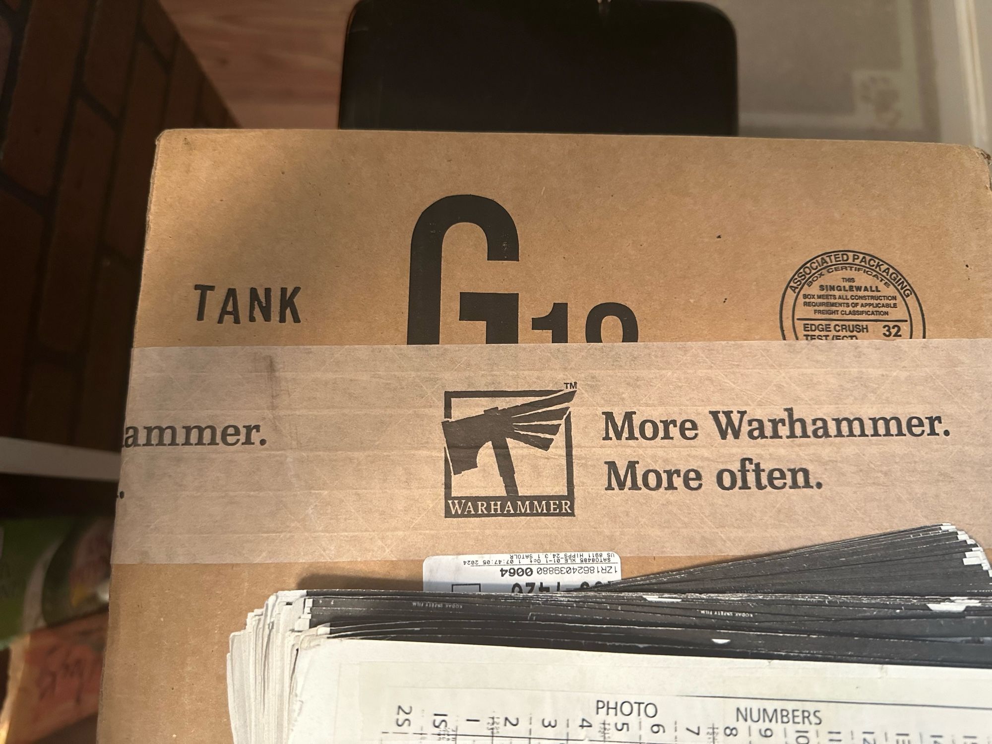 Brown cardboard box with “More Warhammer More Often” tape and labelled as a tank, which it isn’t.