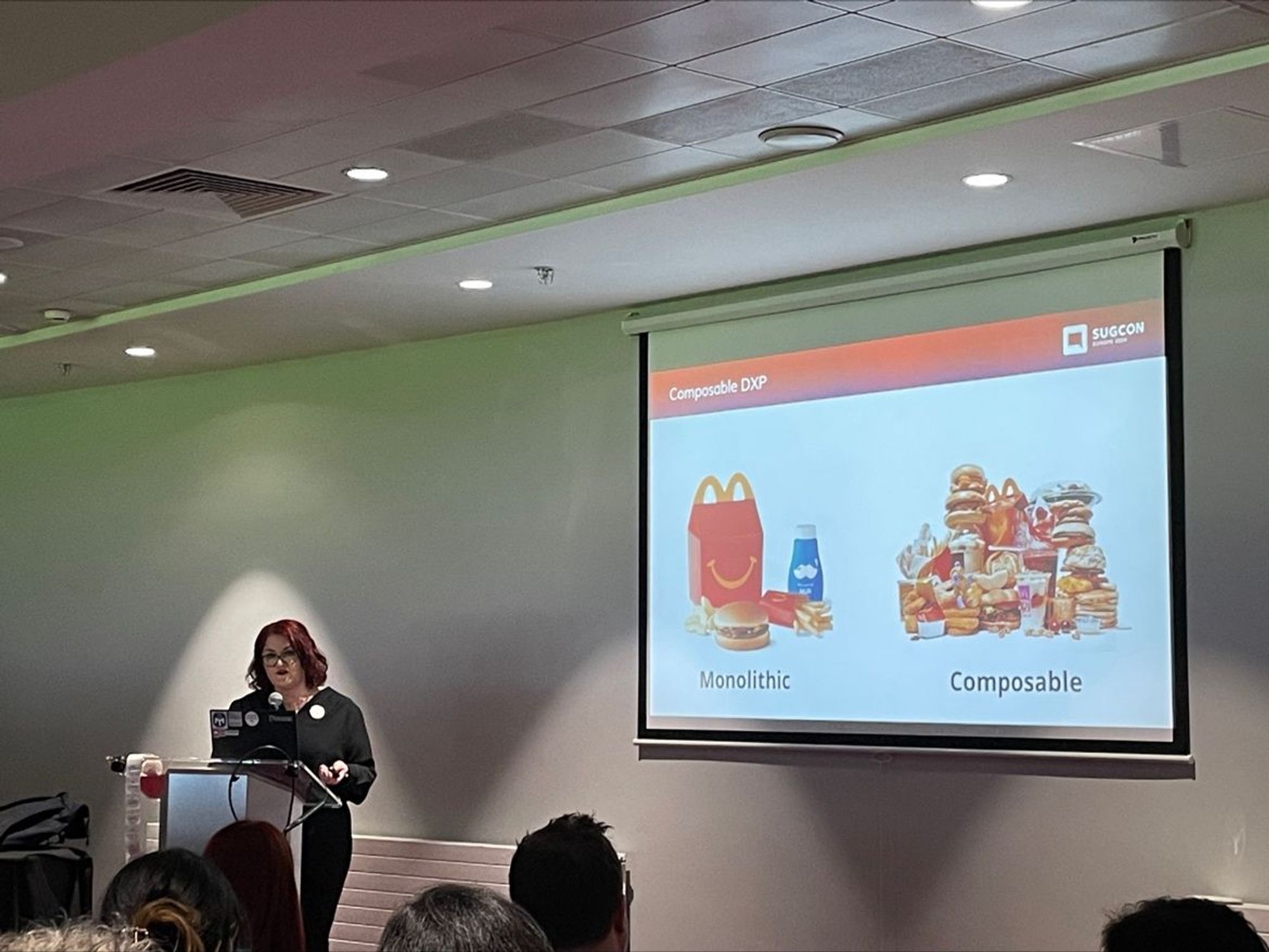 MJ shows a slide titled "Composable DXP" with two food images. On the left is an image of a McDonald's Happy Meal and the subtitle "Monolithic". On the right is a pile of separate McDonald's food items with the subtitle "Composable".

(Photo by Jacqueline Baxter)