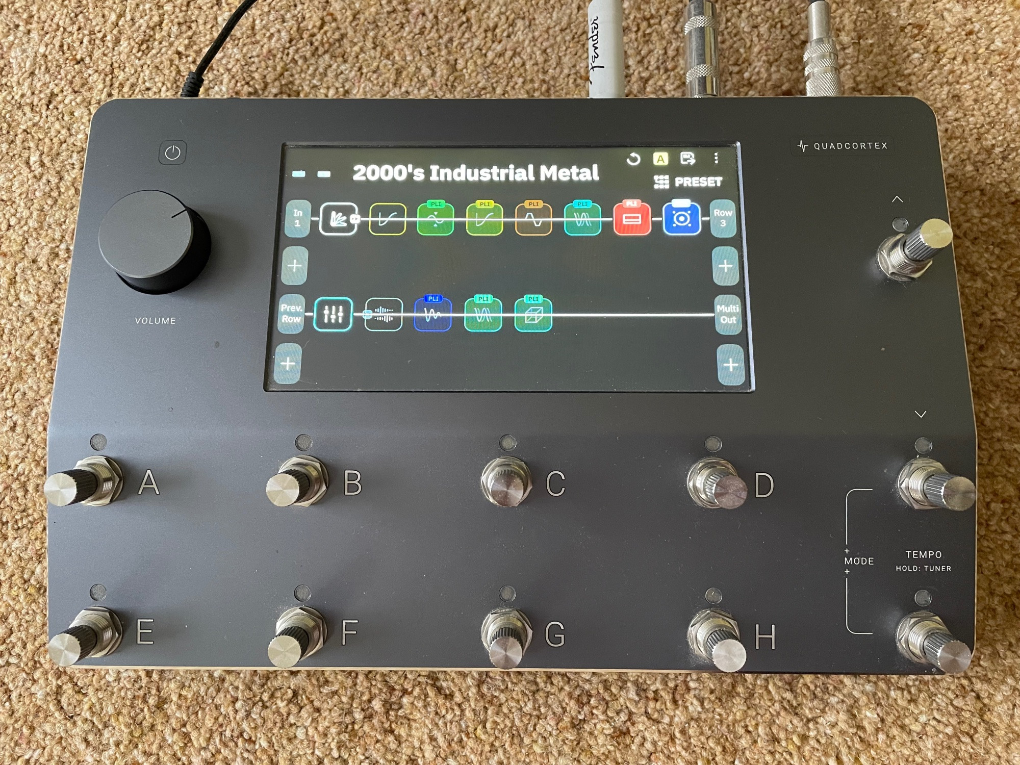 A NeuralDSP Quad Cortex sat on the floor, powered up, showing the “2000’s Industrial Metal” preset selected from the “Archetype: Plini X” plugin.