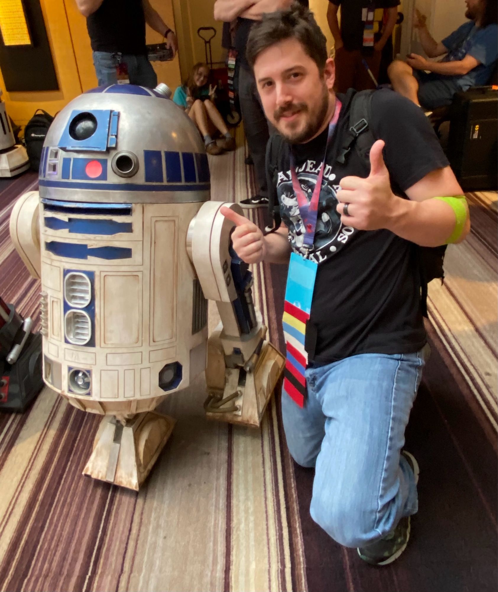 Some white guy kneeling next to the astromech droid, R2-D2.