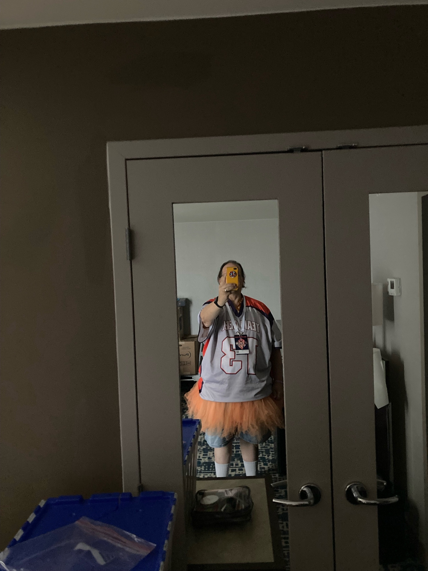 A mirror reflected image of a geek in a jersey and an orange tutu.