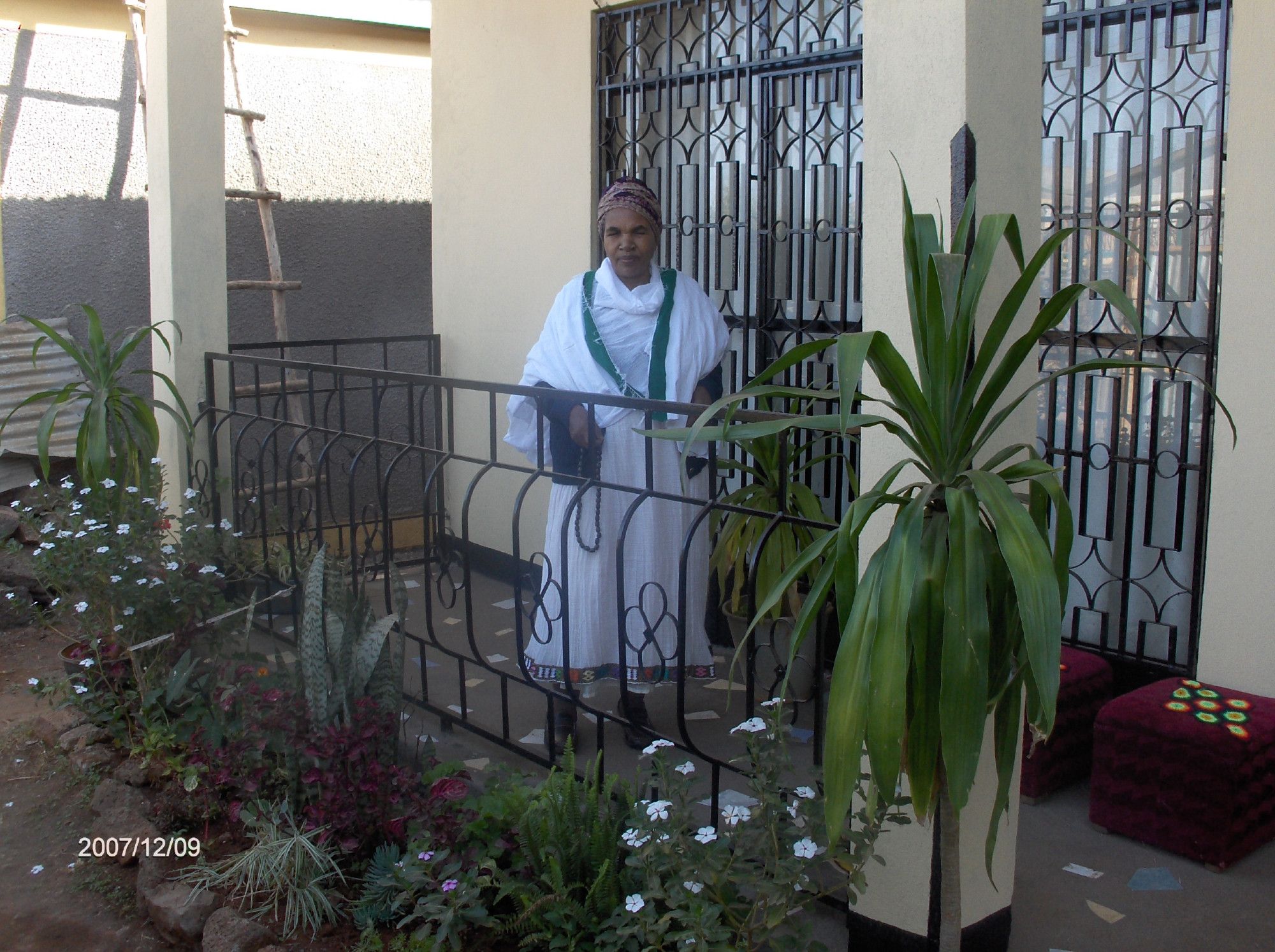 And older amharian lady in traditional dress at the porch of her house