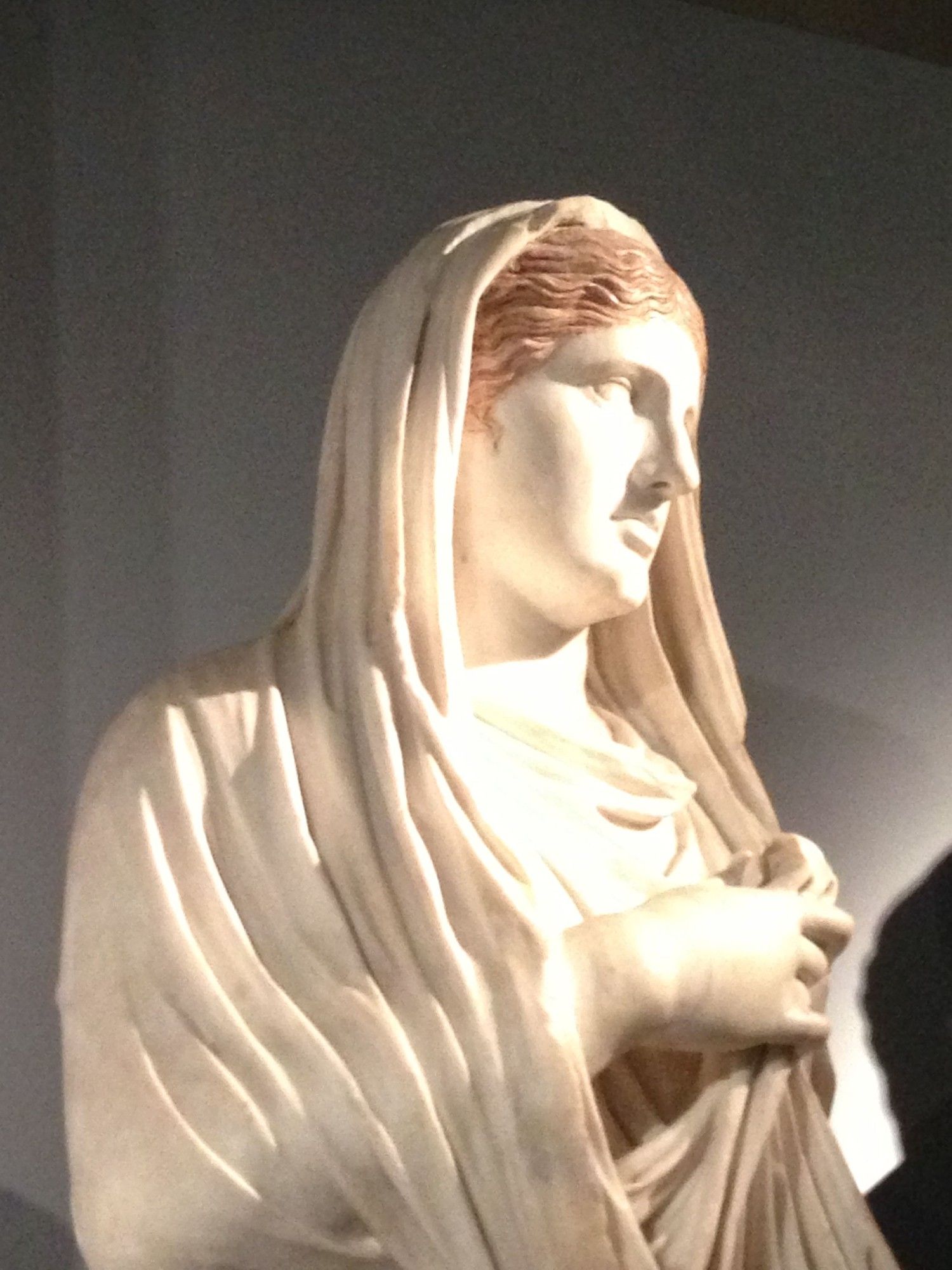 A statue of a woman with her dress folded over her head, the symbol of a priestess. Her hair is coloured red. This is Eumachia, at the British Museum. Not my photo.