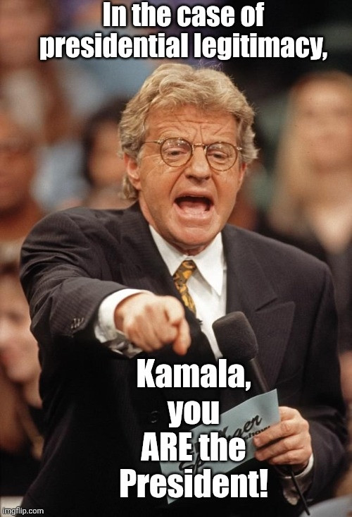 Jerry Springer in a suit & tie holding a notecard & a microphone in one hand & pointing with the other, saying, "In the case of presidential legitimacy, Kamala, you ARE the President!"