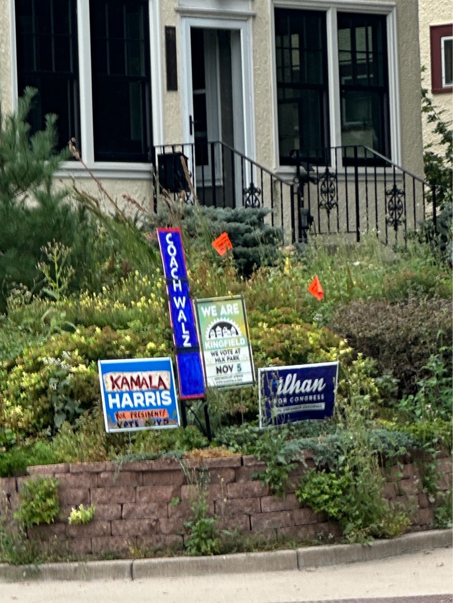 Various political yard signs in front of a neighborhood home.