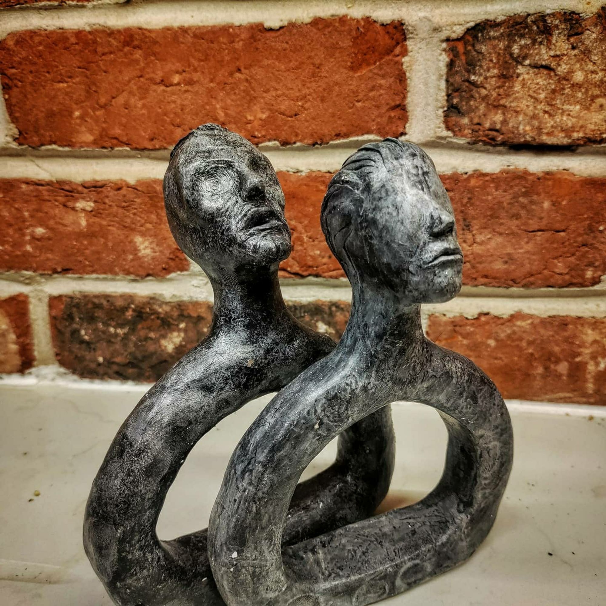 2 stylized busts, eyeless with metallic finish