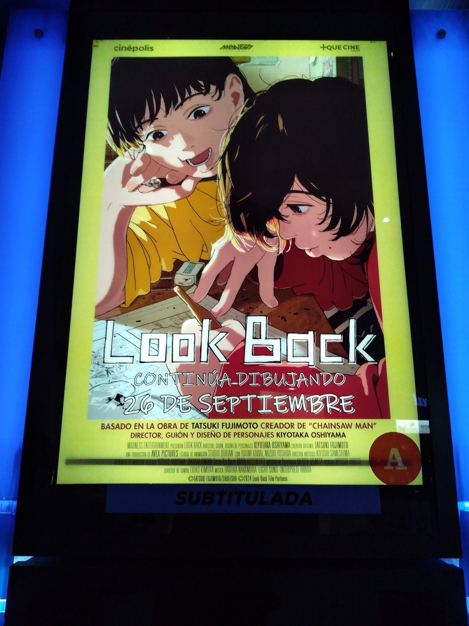 Poster de la película "Look Back, continúa dibujando". Dos niñas, una con la mano en la mejilla hablando mientras mira a otra chica dibujando un boceto.