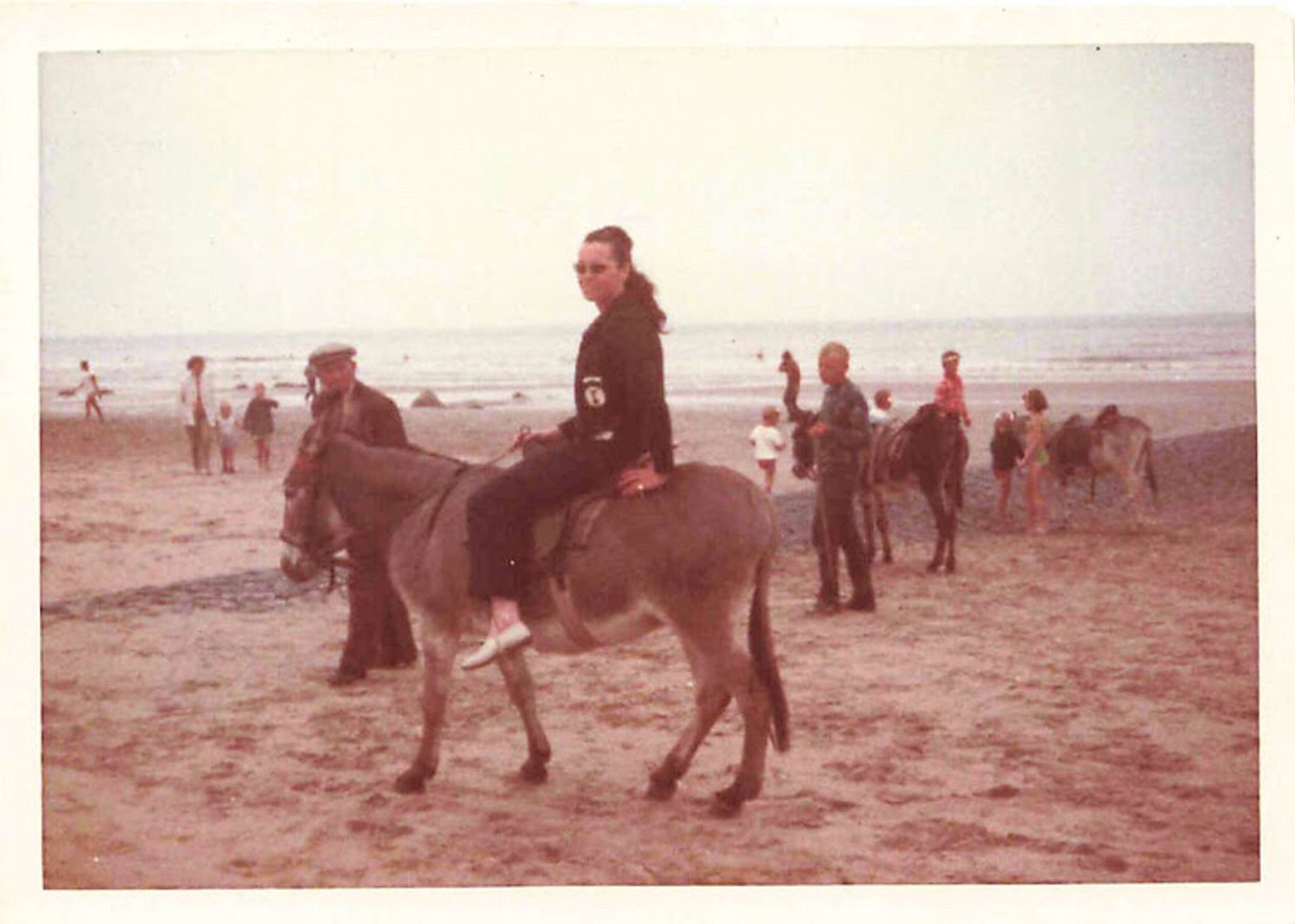 Frau auf einem Esel am Strand