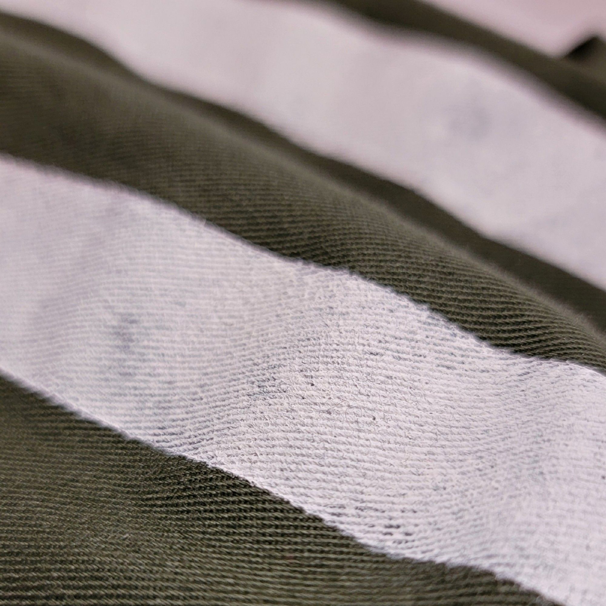 Stenciling detail to show a stripe of white paint on olive twill fabric