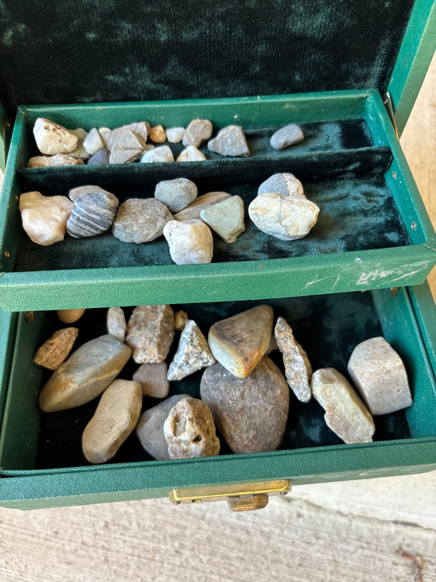 Photo of a green jewelry box, opened to show lots of nondescript grey pebbles. Most are metamorphic rocks, with a few granites and vein quartz.