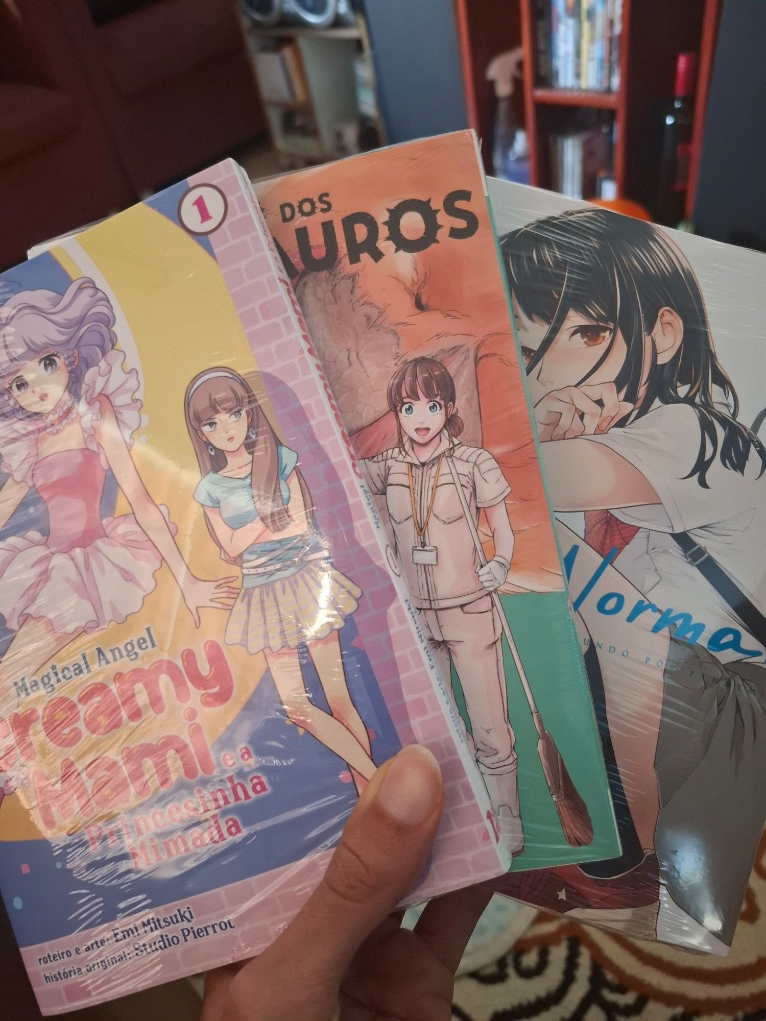 Foto minha segurando os volumes 1 de Creamy Mami, Santuário dos Dinossauros e New Normal